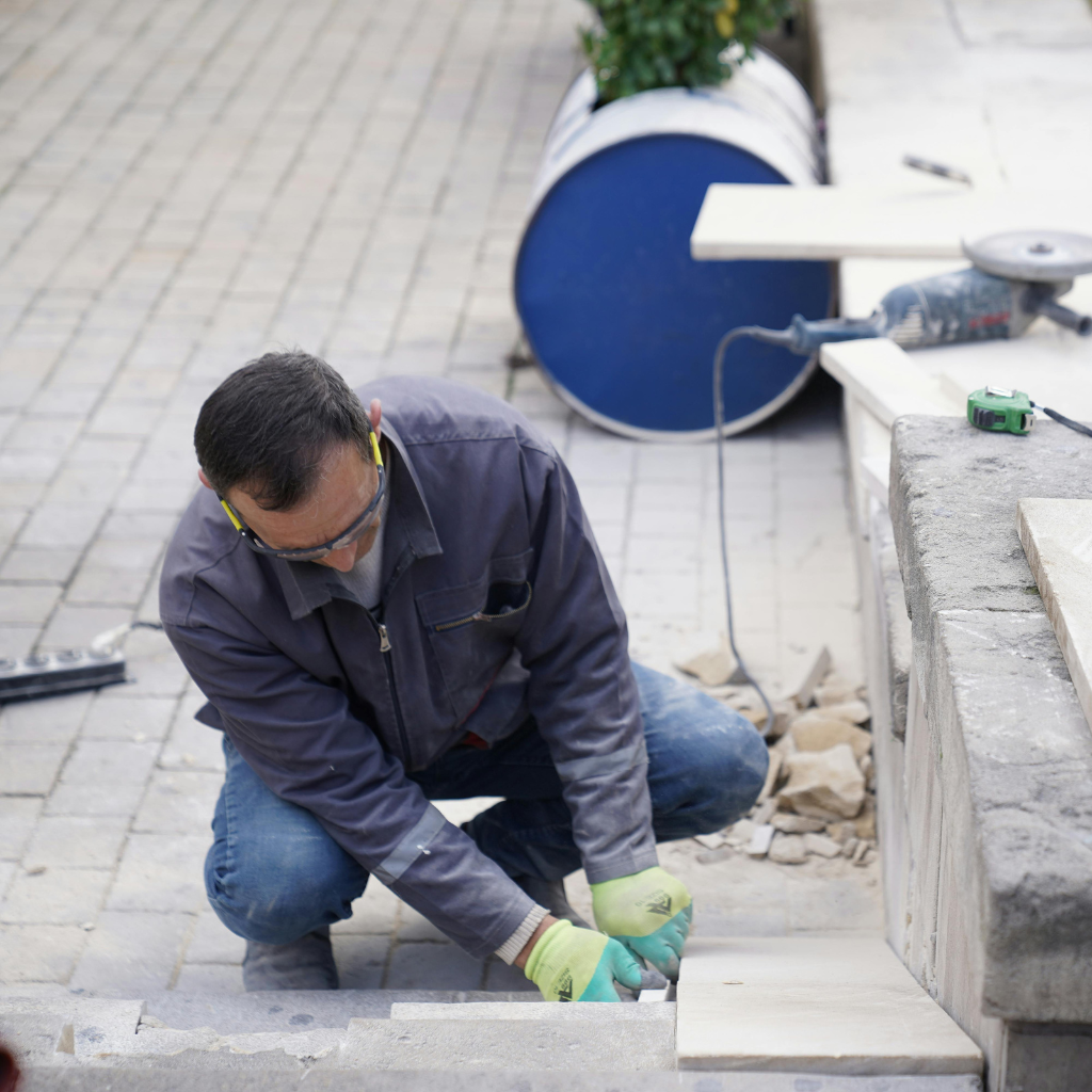 Man wearing safety glasses and gloves repairing concrete steps