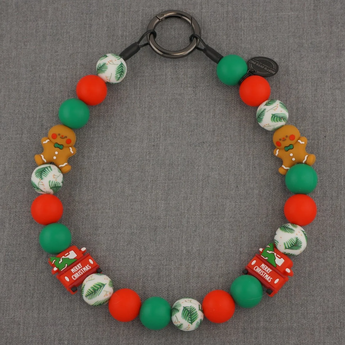 Featuring festive red and green beads, playful gingerbread men, adorable Christmas trucks, and charming evergreen accents, this decorative necklace is bursting with holiday cheer.