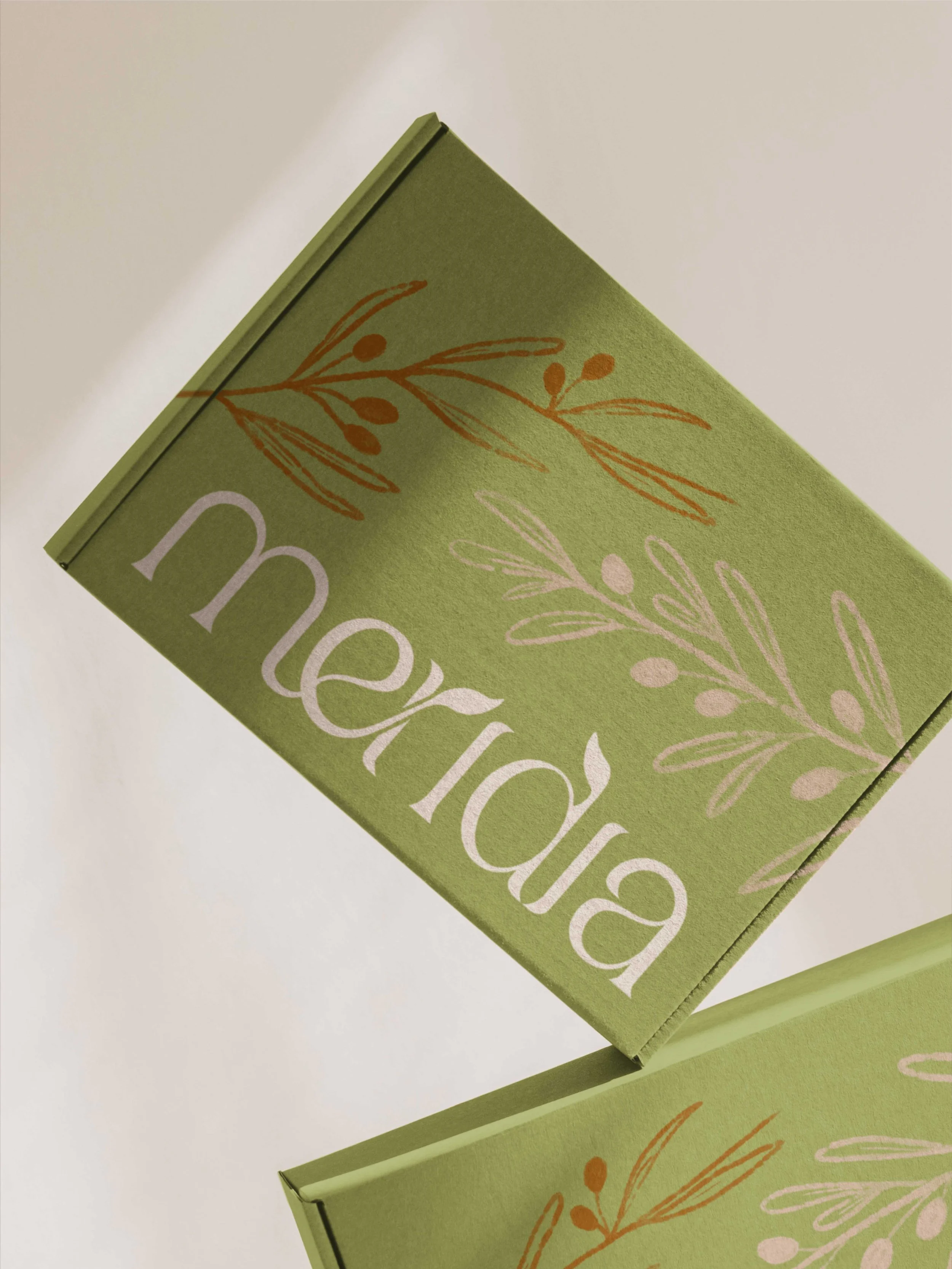 Vista detallada de la caja de envío verde oliva con el logotipo de Meridia y motivos botánicos impresos.