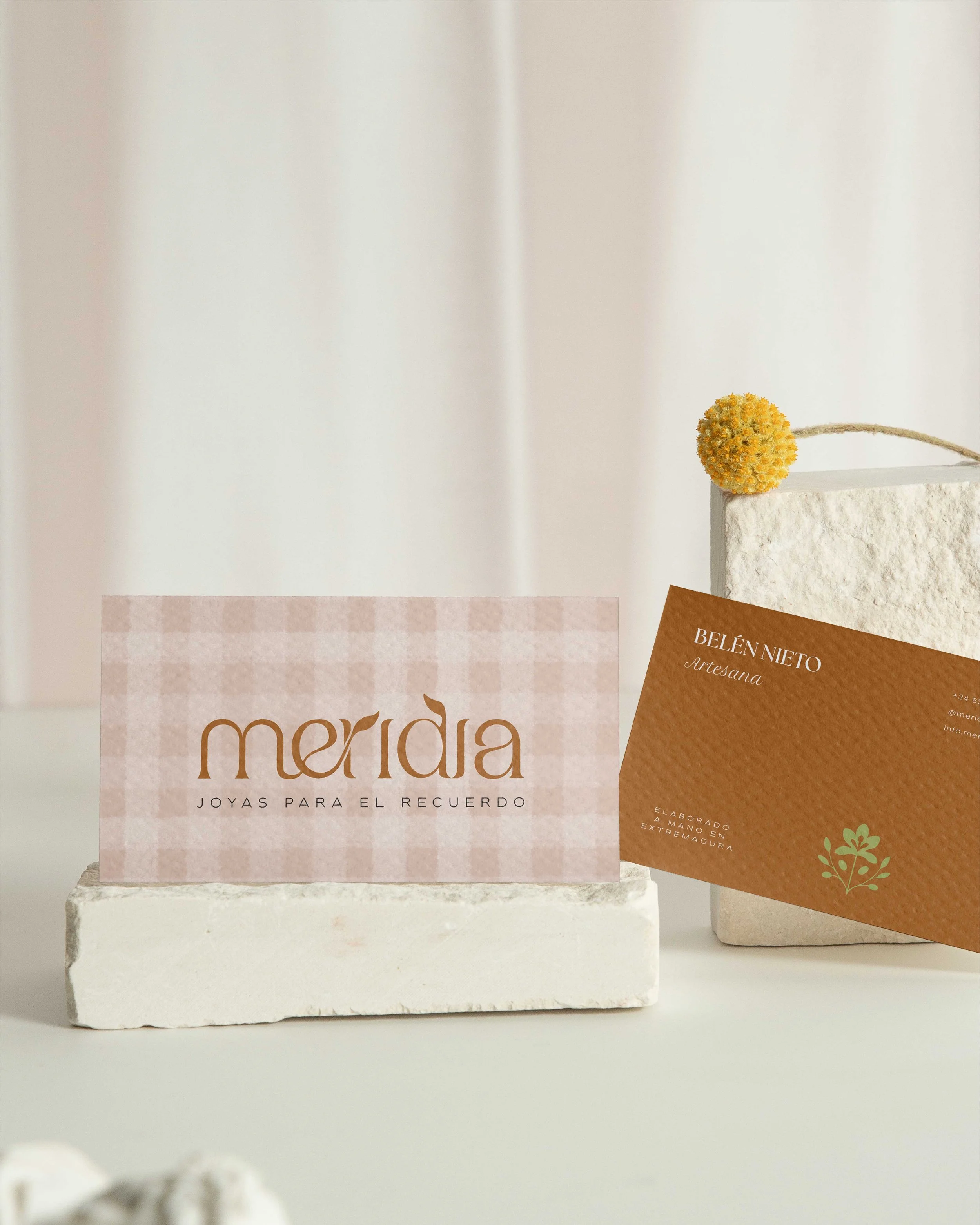 Tarjetas de visita de Meridia sobre piedra natural destacando el contraste entre el patrón vichy y la identidad visual.