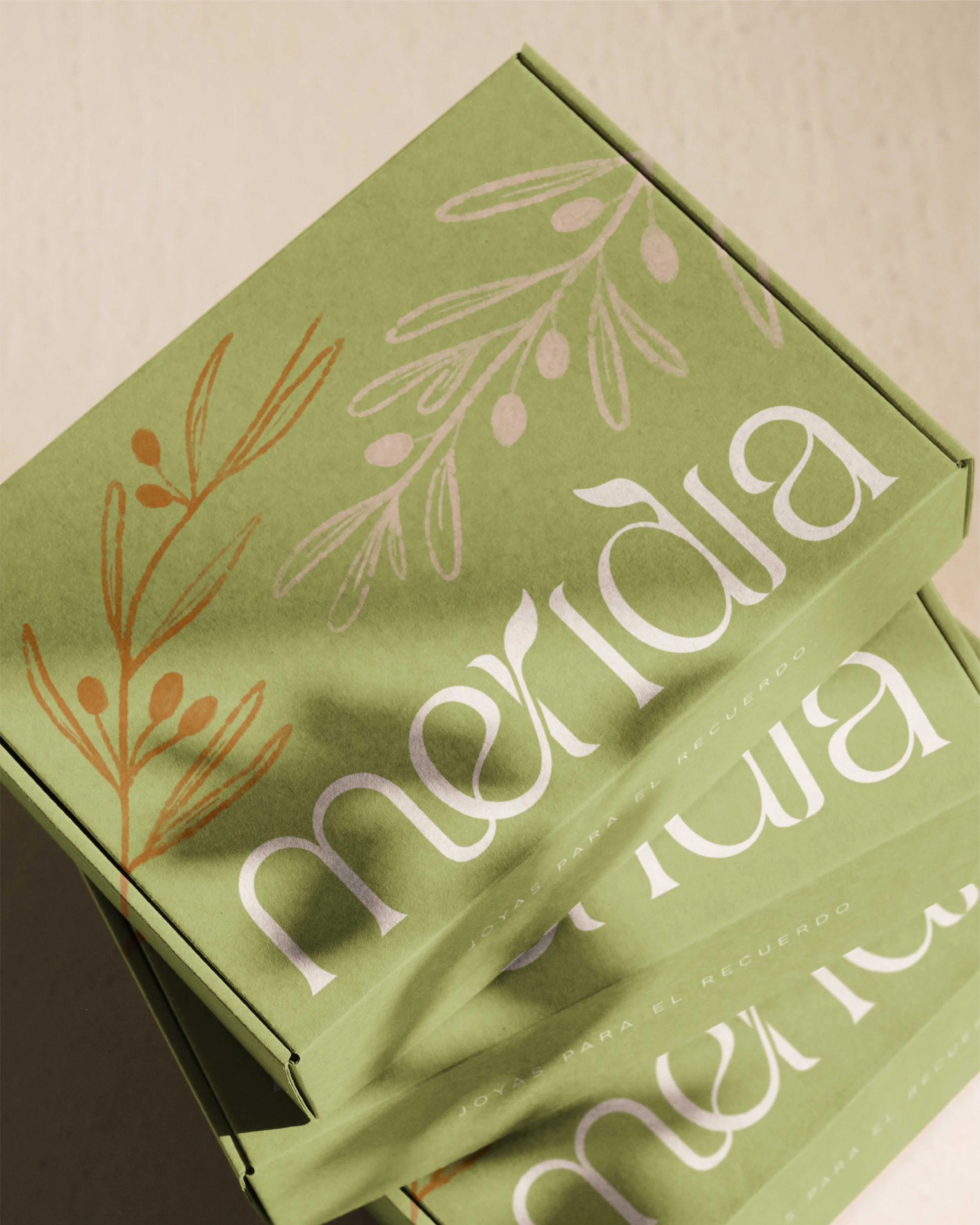 Pilas de cajas de cartón verde oliva con el logotipo de Meridia preparadas para el envío de joyería fina.