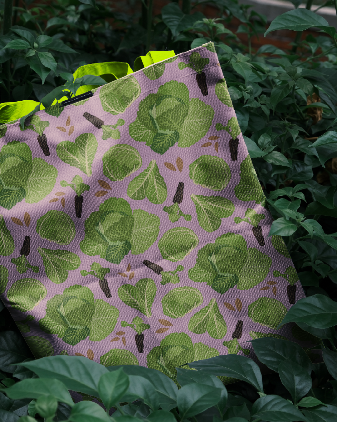Bolsa de tela con estampado de hojas verdes entre plantas.