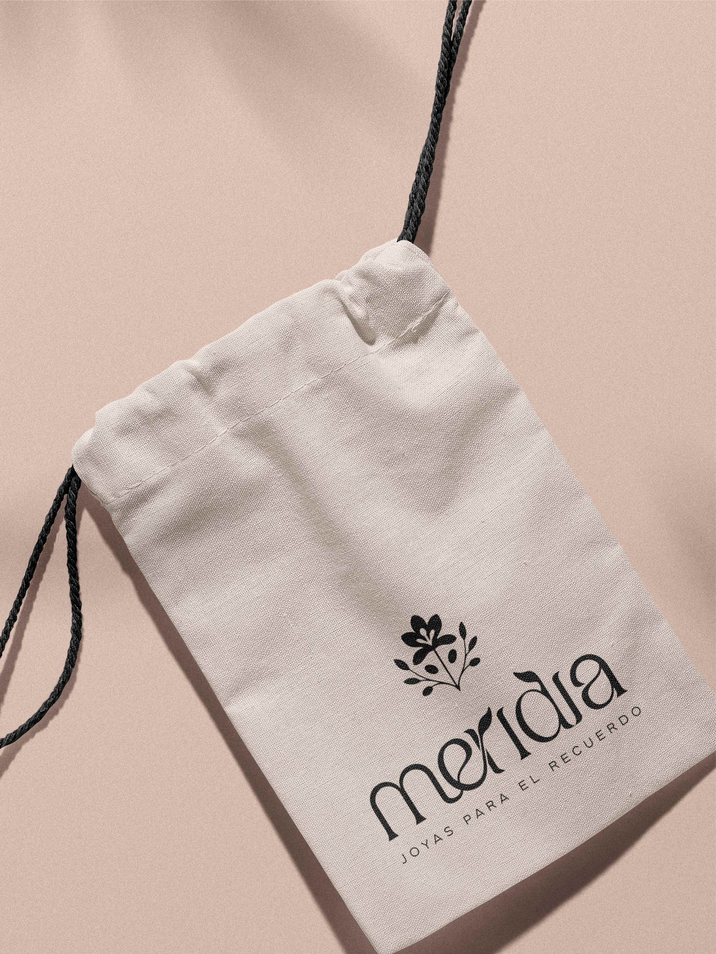 Bolsita de tela de algodón orgánico con el logotipo de Meridia impreso ideal para el empaquetado sostenible de joyería de autor.