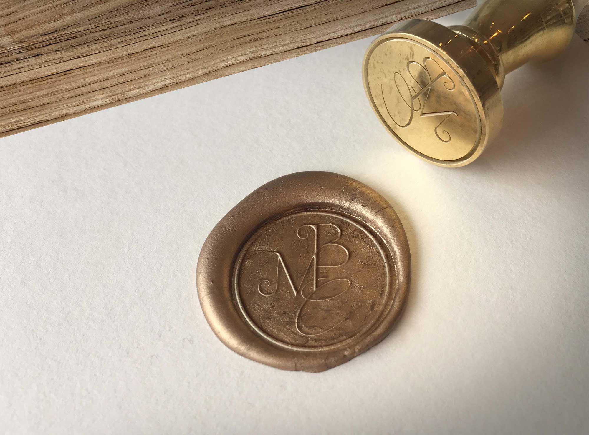 Detalle de sello de lacre dorado con el monograma MBC y herramienta de sellado manual para la artista Mamen Barrena Coranti.