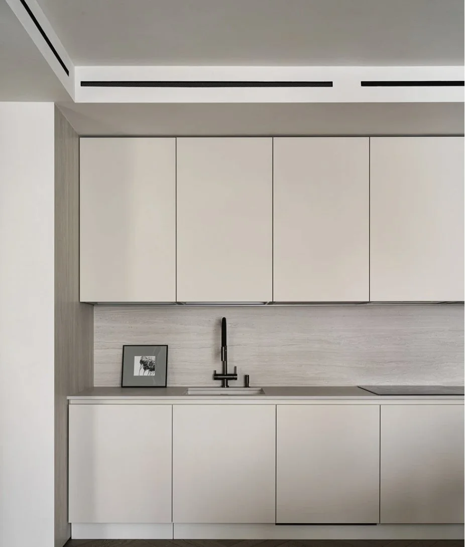 Minimalist kitchen with white cabinets, black faucet, and a framed photo on the countertop.