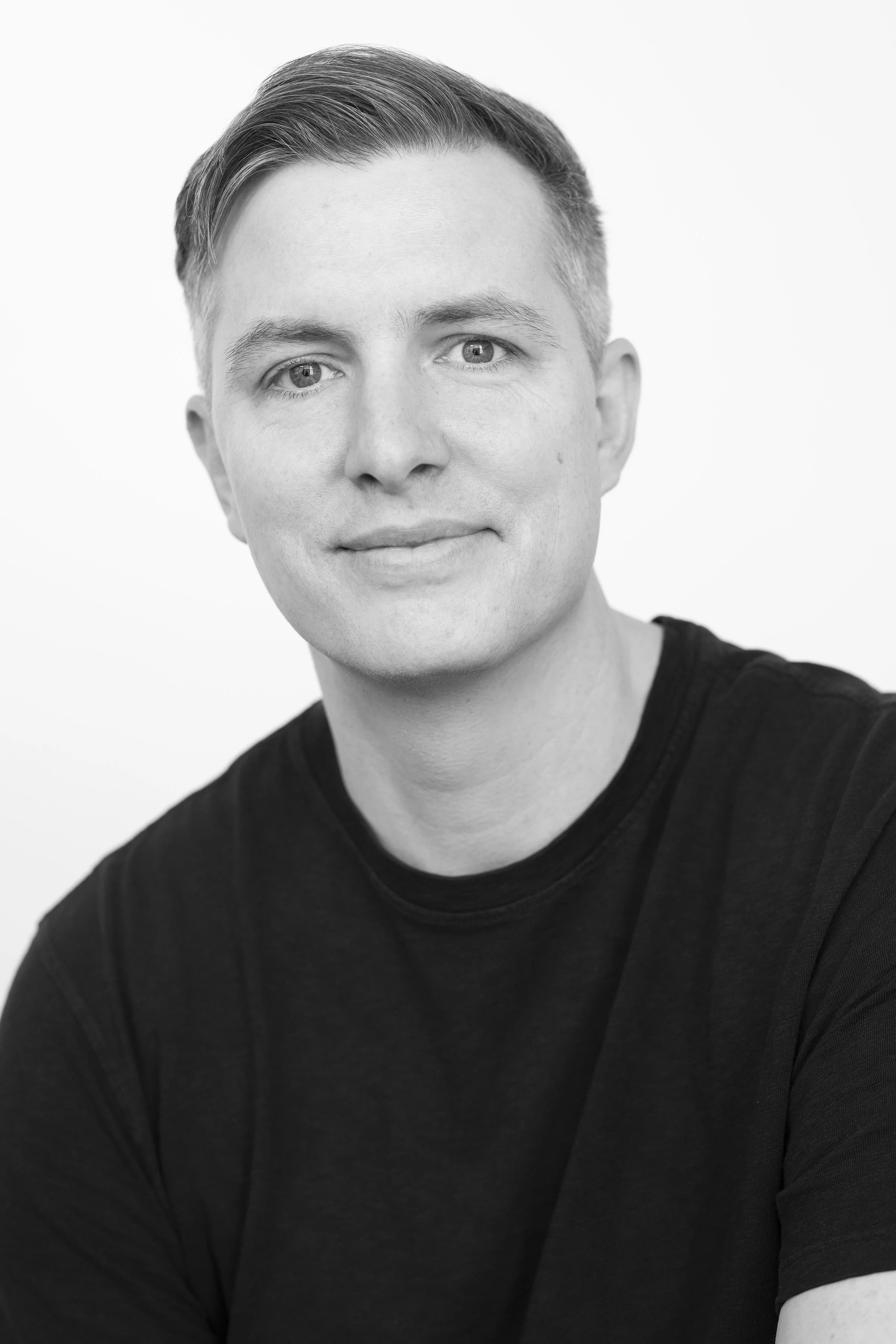The image is a headshot of Evan Hanczor in front of a wood wall.