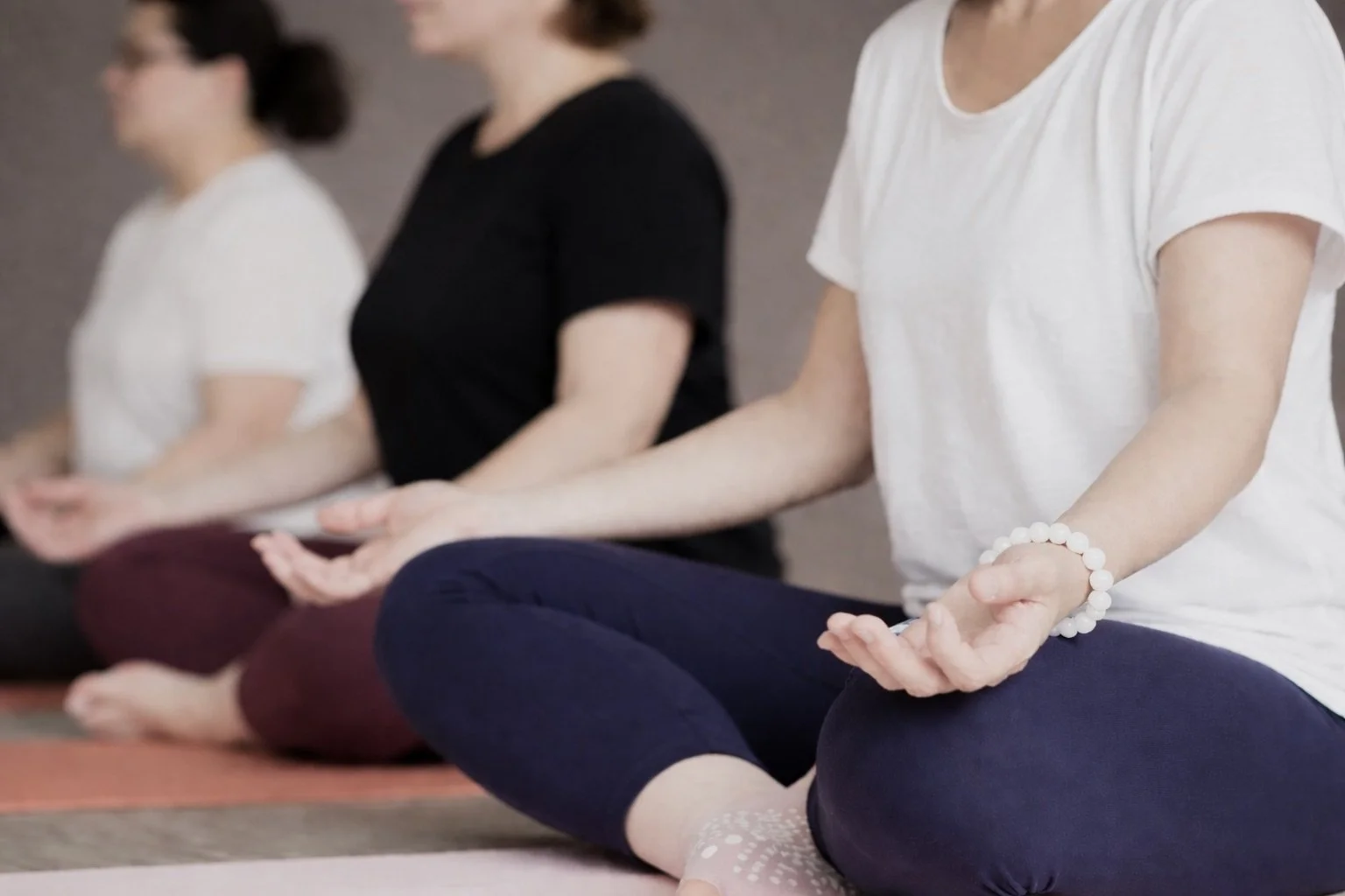 Kundalini yoga class with seated participants in a studio, taught by Yogi Bhajan, held Thursdays from 9:30 to 10:30 AM. Website: everybodyyogaandwellness.com. Logo of Everybody Yoga & Wellness.
