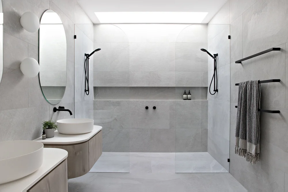 Completed bathroom with twin basins and a wide frameless shower