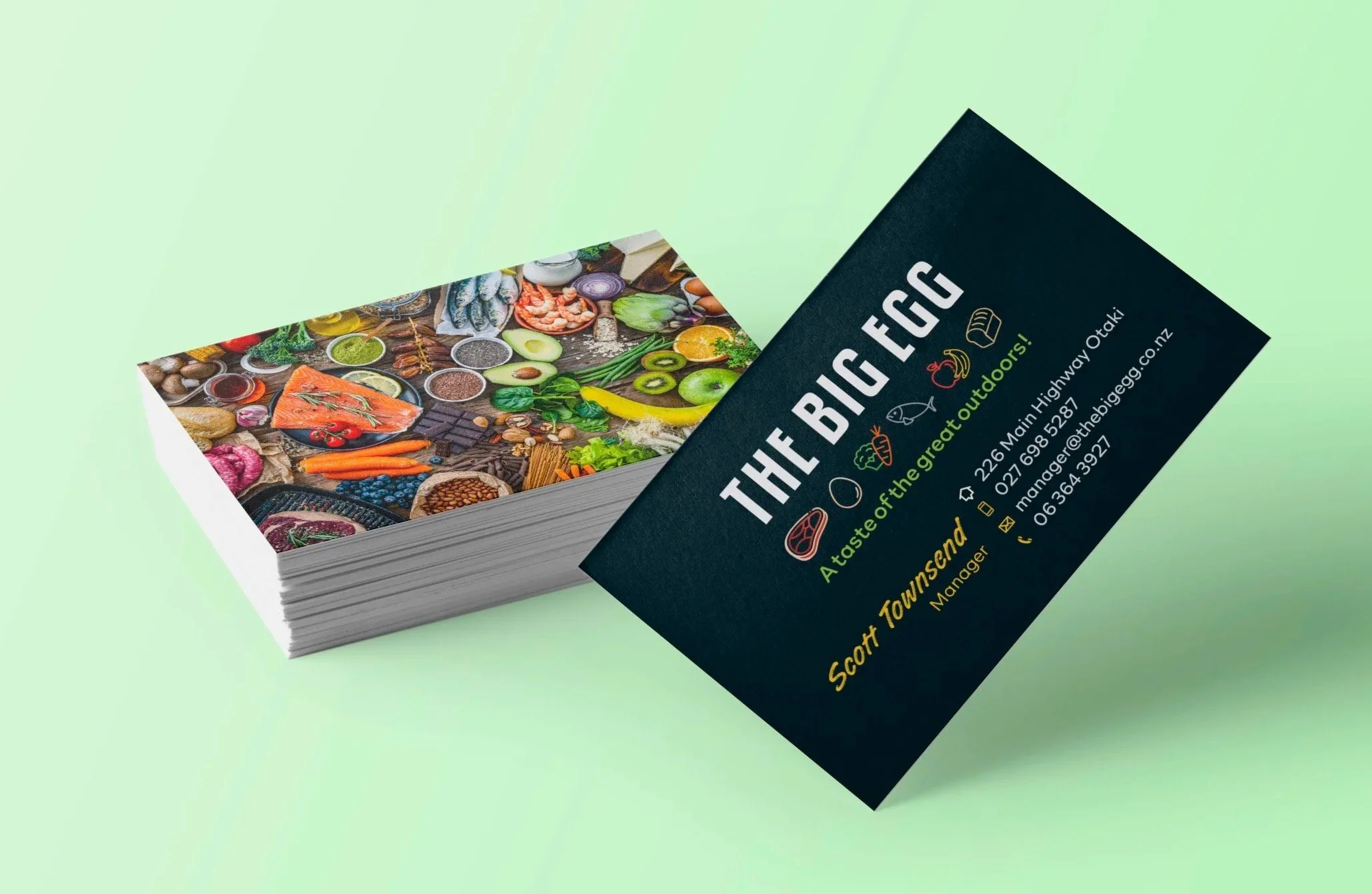 Black business cards on a light green background, showing the front with the Big Egg logo and contact details, and the whole back of the card features a montage showing a variety of food.
