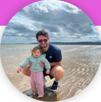 Adult and child on a sandy beach with cloudy sky.