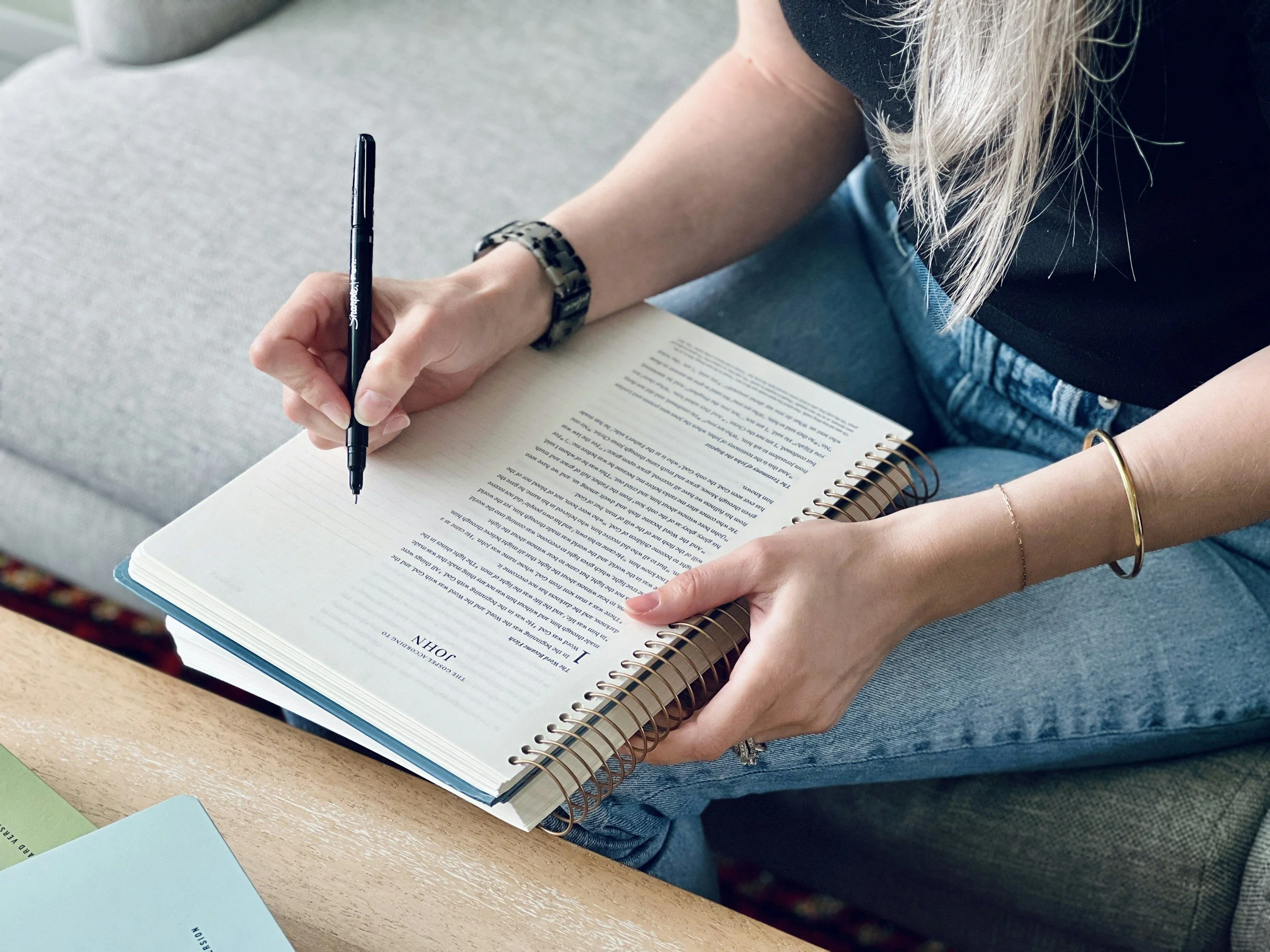Woman with notebook on her lap making notes with a blaack pen