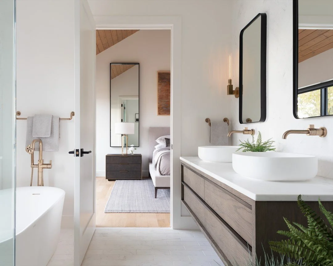 The sunny southern exposure of this master bathroom inspired us to use white marble tiles for a luxe, airy feel, accented with warm brass and contrasting dark metals. This bright, inviting little oasis is one of our favorite rooms in the house. #nort