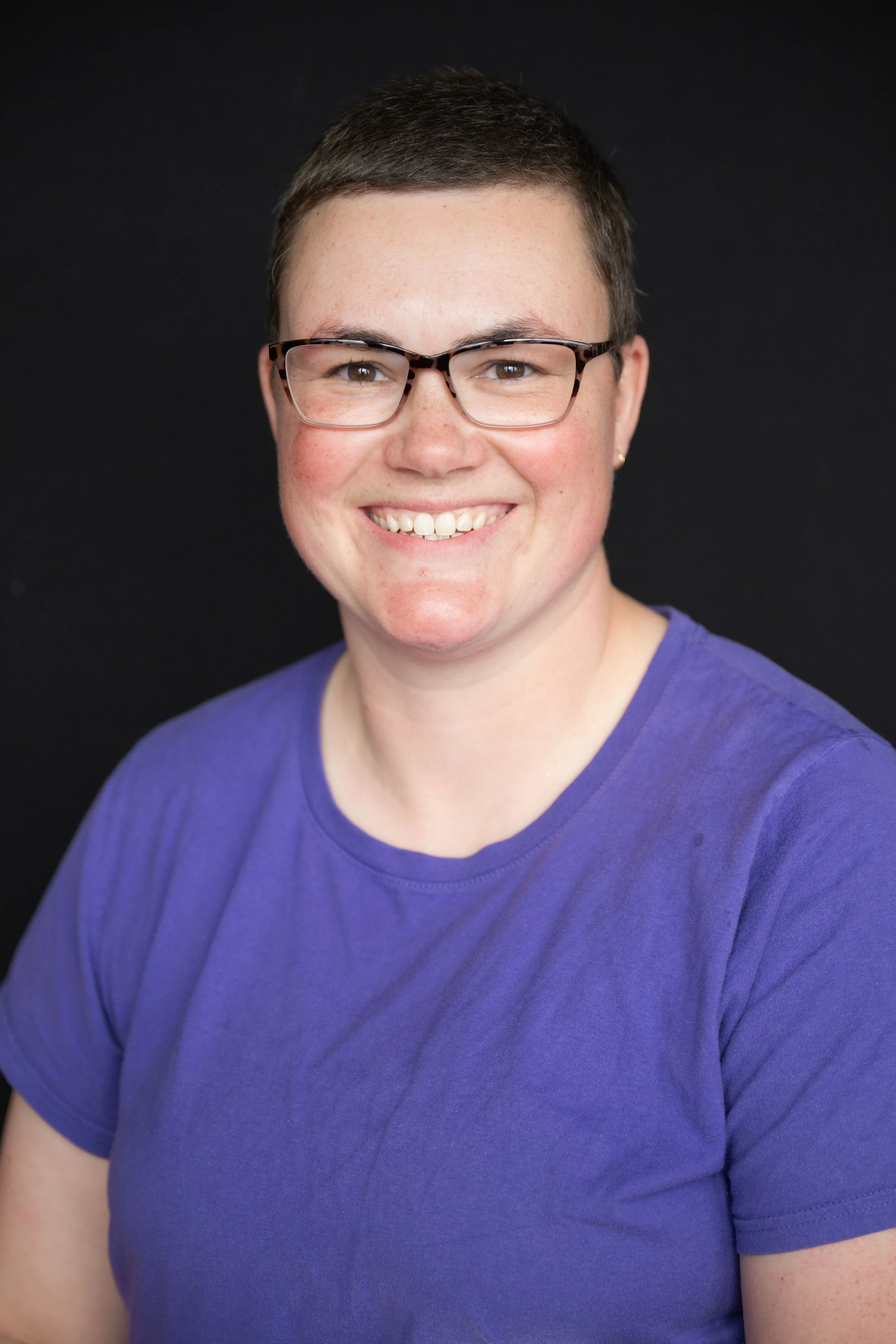 Person smiling, wearing glasses and a colorful scarf.