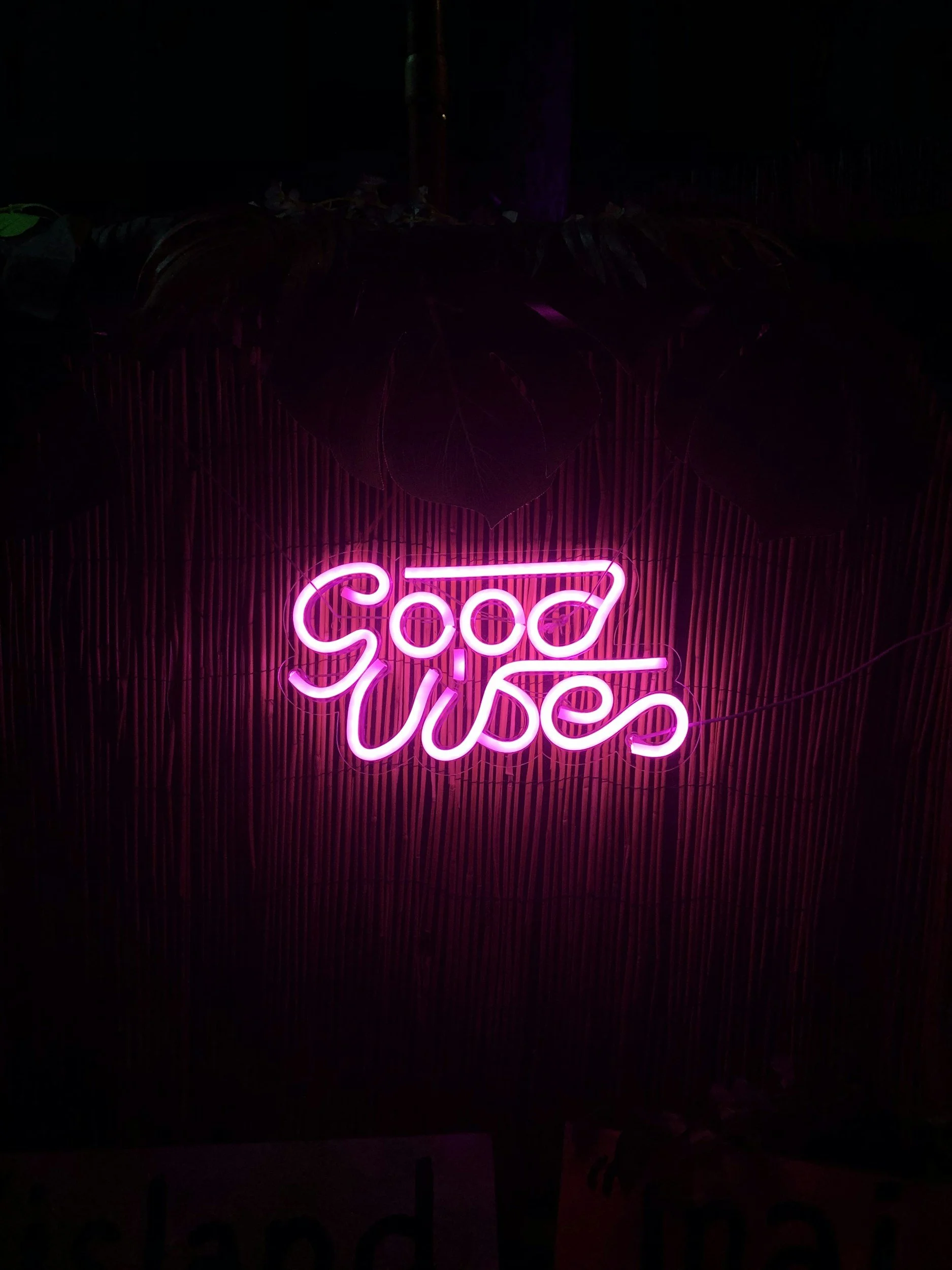 Pink neon sign reading 'Good Vibes' against a dark background.