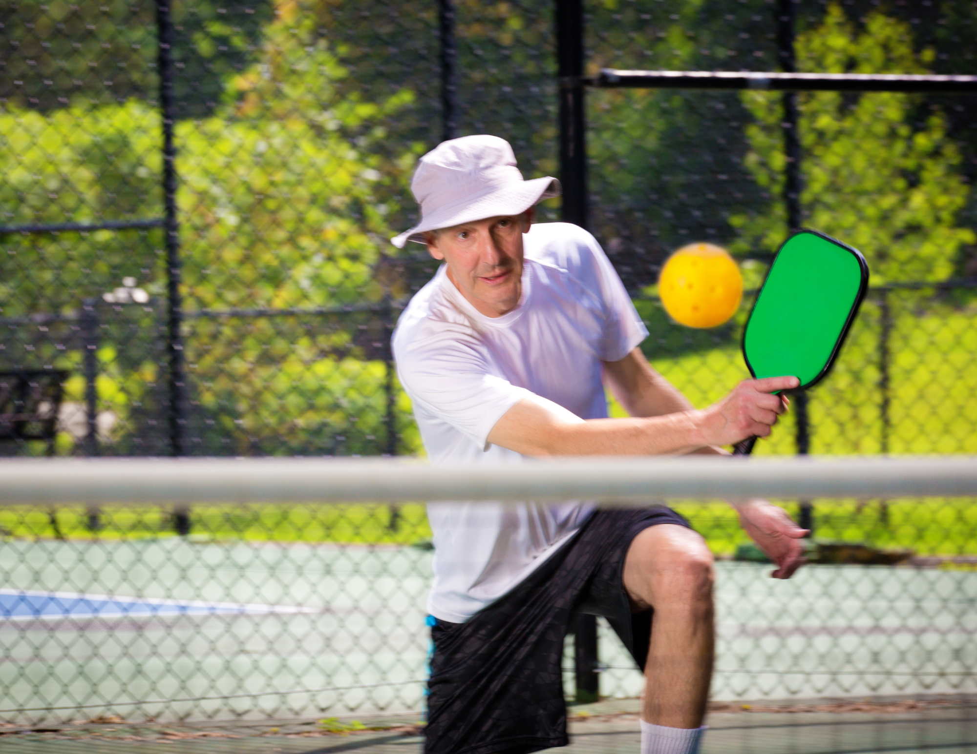 A man playing pickleball during the Grapes and Glory athletic competition at an adult summer camp.