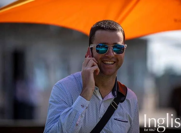 Image of young man with reflective sunglasses on talking on the phone and smiling at the camera