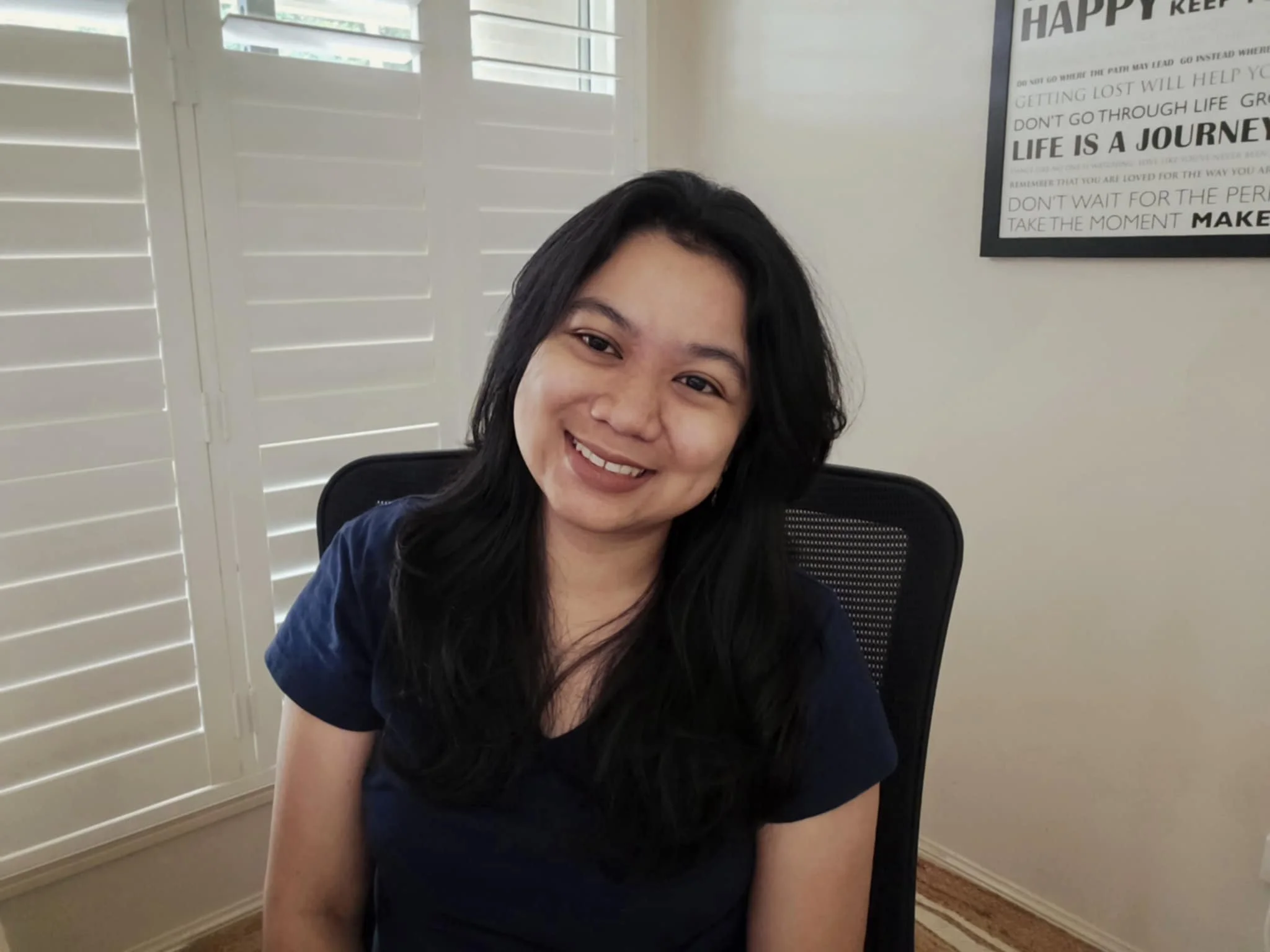 Marianne Warren, Youth Group Leader, A woman with black hair smiling in a room with white plantation shutters and a motivational poster on the wall.