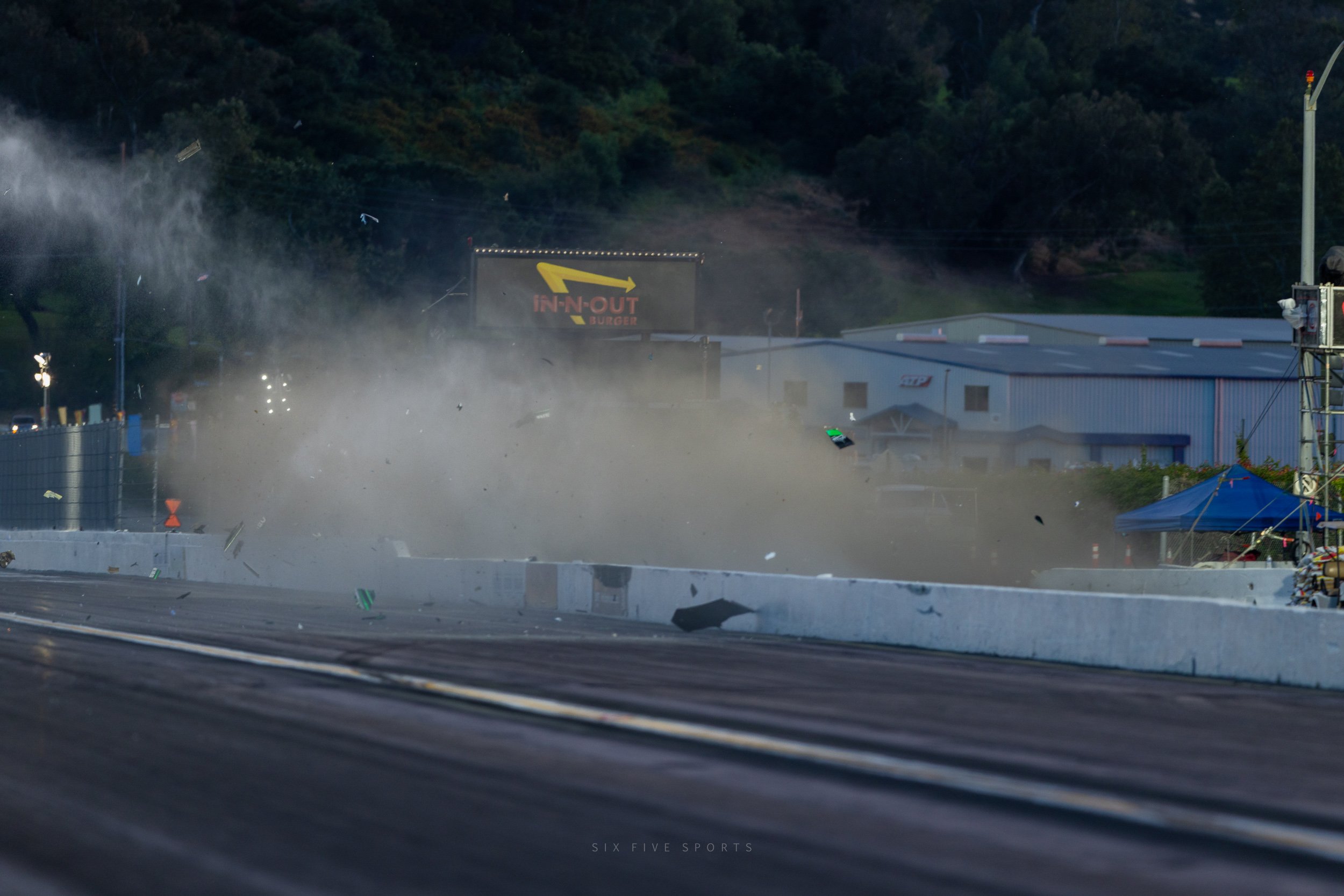 Debris from James Steven's Top Alcohol dragster still in the air as he catapulted into the catch fencing