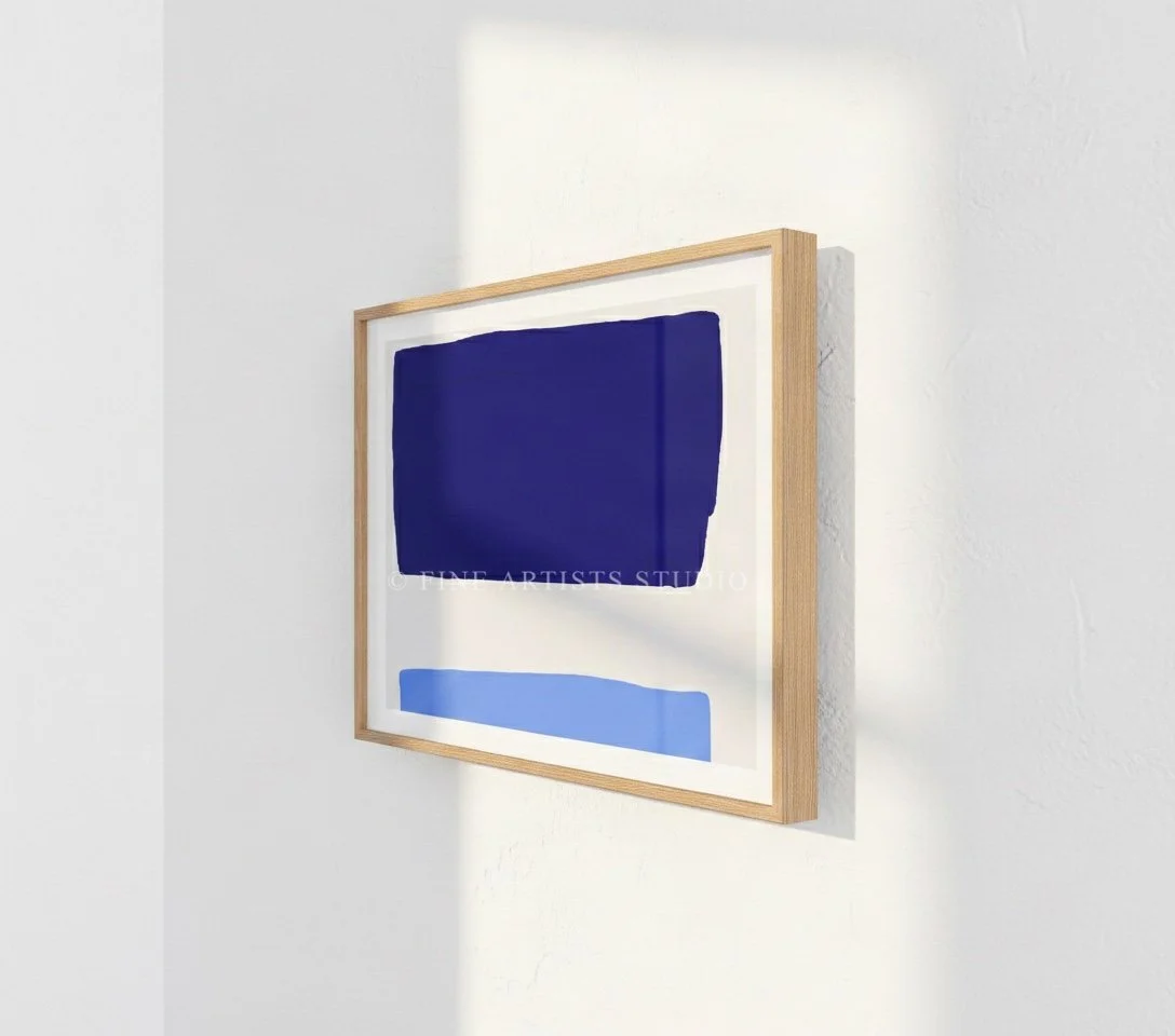 Close-up angled shot of a framed abstract geometric print showcasing the clean cobalt and sky blue shapes in a contemporary interior setting.