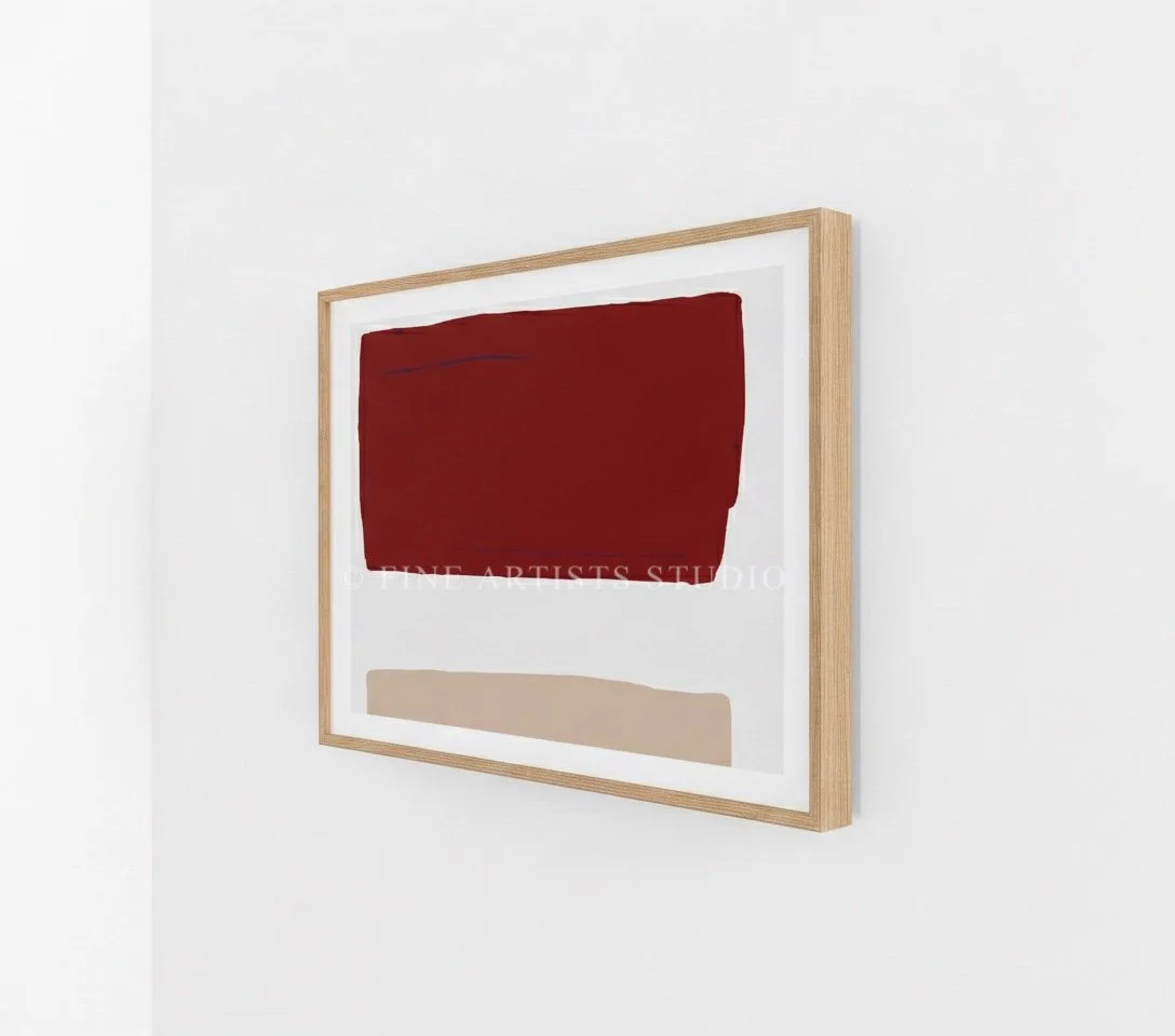 Close-up angled shot of a framed abstract print showcasing clean crimson red and pastel pink geometric art block shapes.