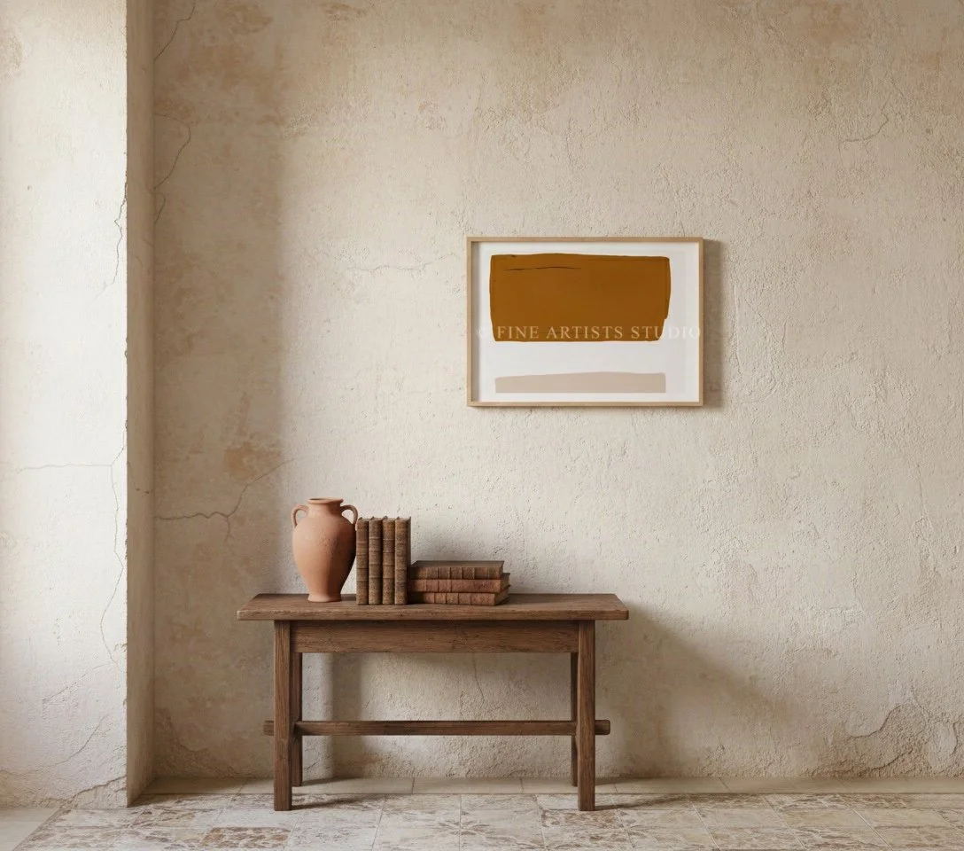 Framed brown and pink geometric print displayed on a modern wooden sideboard cabinet next to a sleek table lamp and minimalist ceramics.