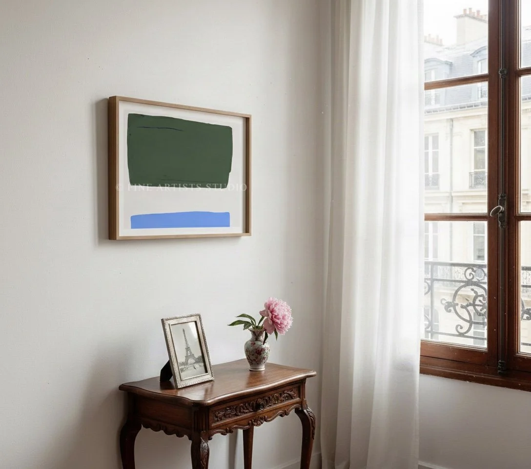 Angled view of a framed modern gradient print displayed in a sunlit hallway over a minimalist console table with design objects.