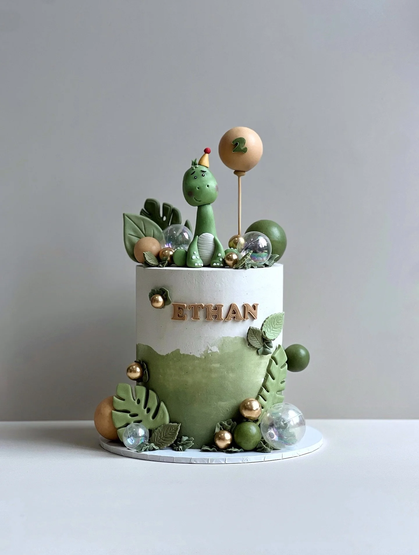 Meet the star of the show: a two-year-old dinosaur ready to celebrate Ethan&rsquo;s big day! From the hand-sculpted T-Rex (okay, maybe it&rsquo;s a Diplodocus 🤭) to the lush jungle greenery and golden accents, this cake is 100% made with love and al