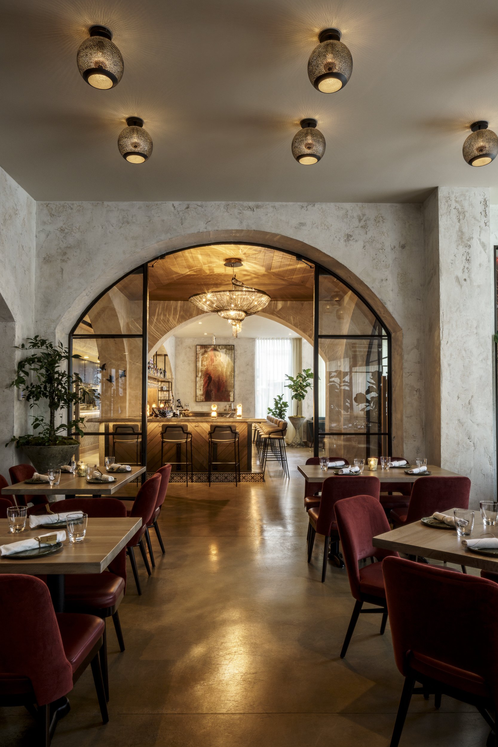 Elegant restaurant interior with arched doorway, chandelier, and modern decor.