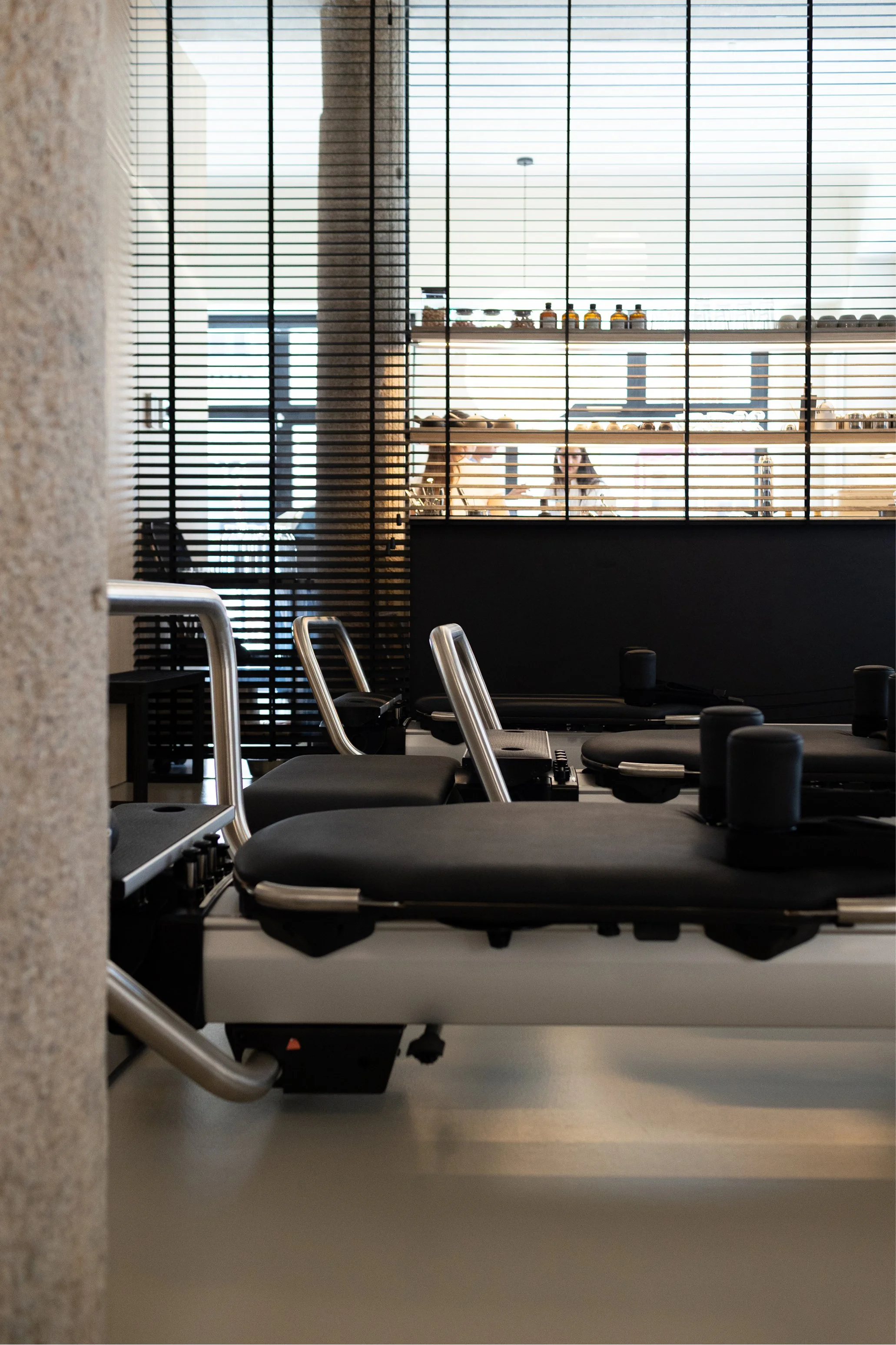 Sala di fisioterapia con lettini e attrezzature, vista attraverso una grata in metallo