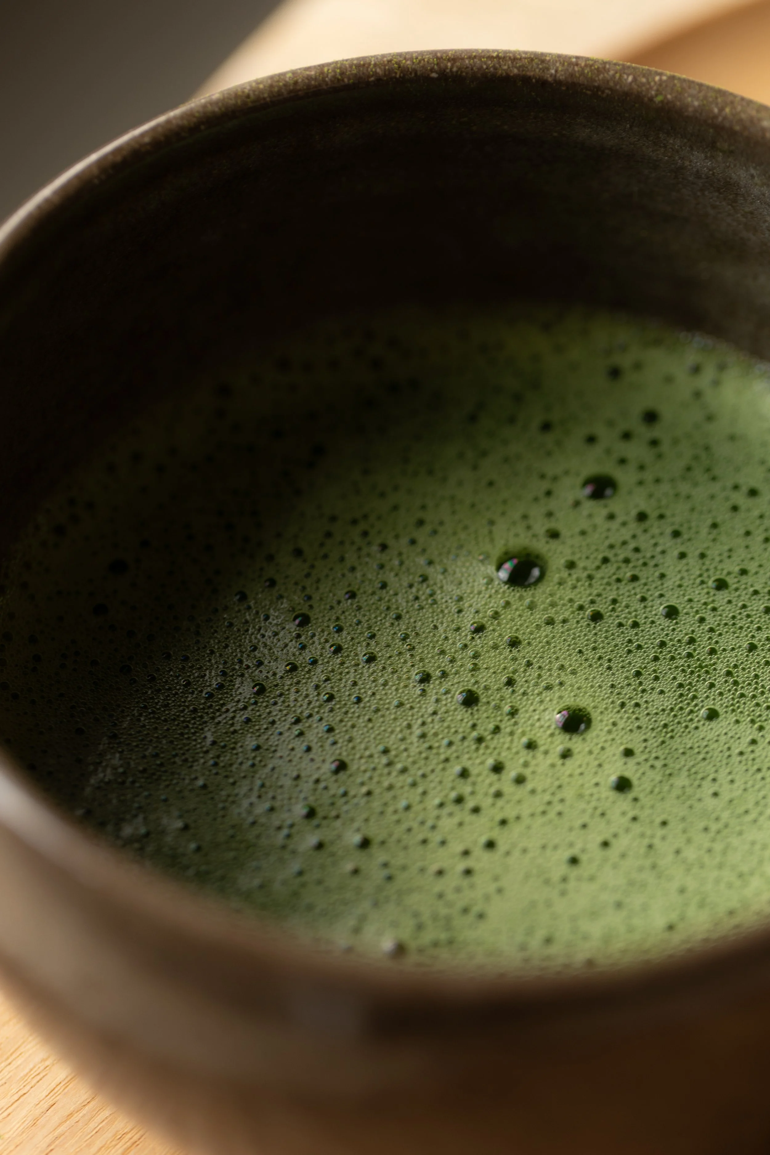Una ciotola con matcha in polvere e acqua che rotea, creando una schiuma verde.