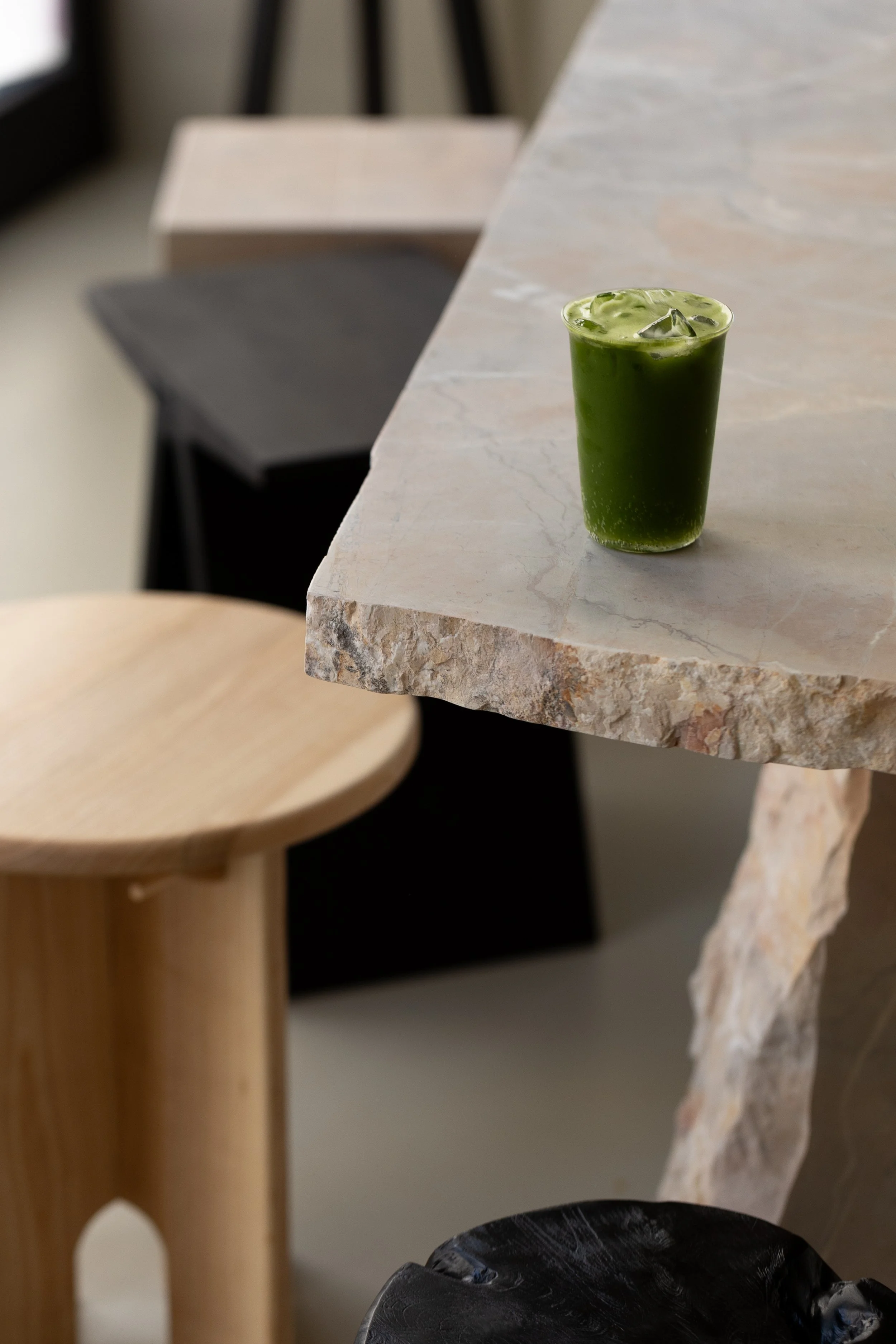 Un bicchiere di frappé verde con ghiaccio su un tavolo di marmo.
