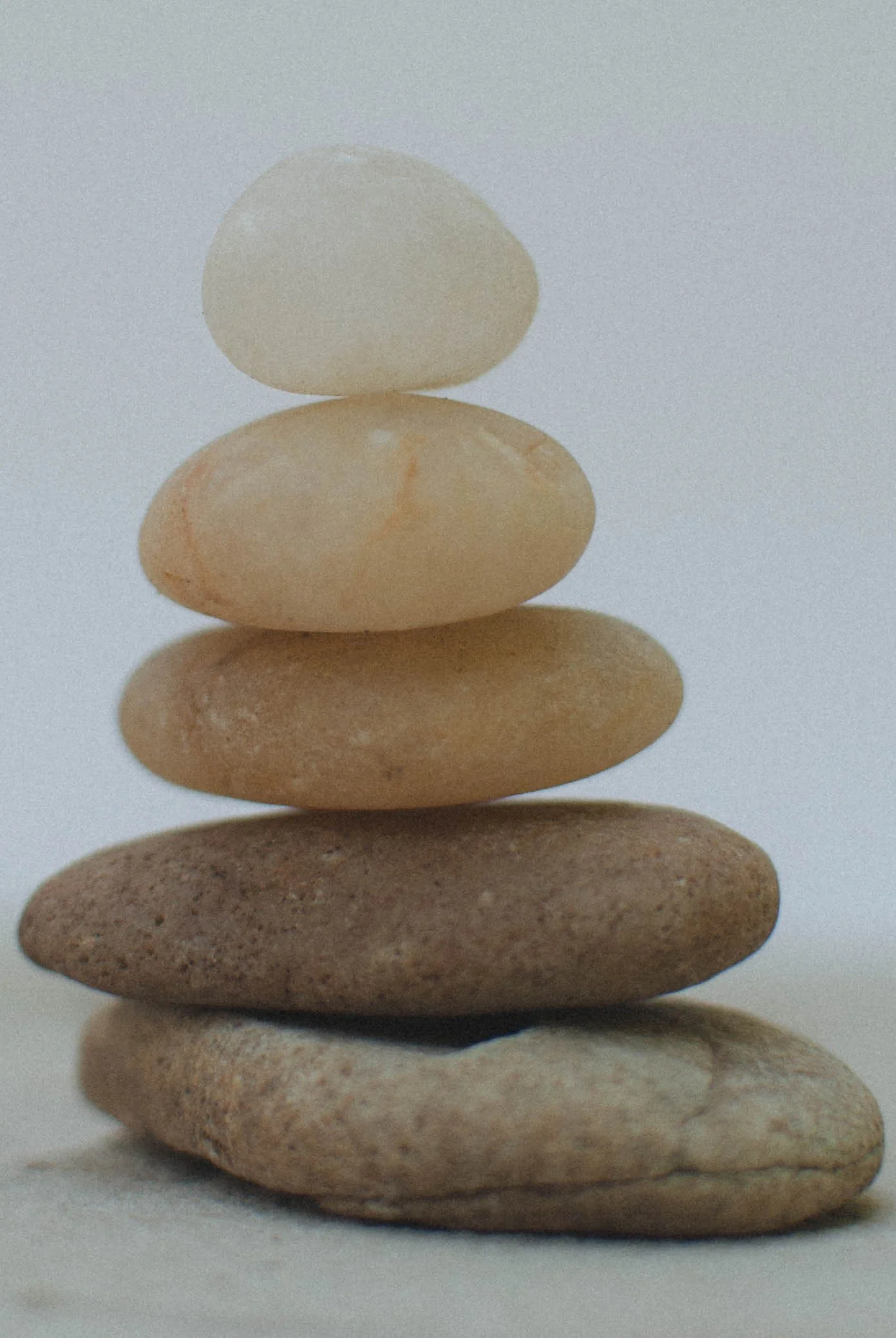 Stacked smooth stones arranged in a vertical line on a white background.