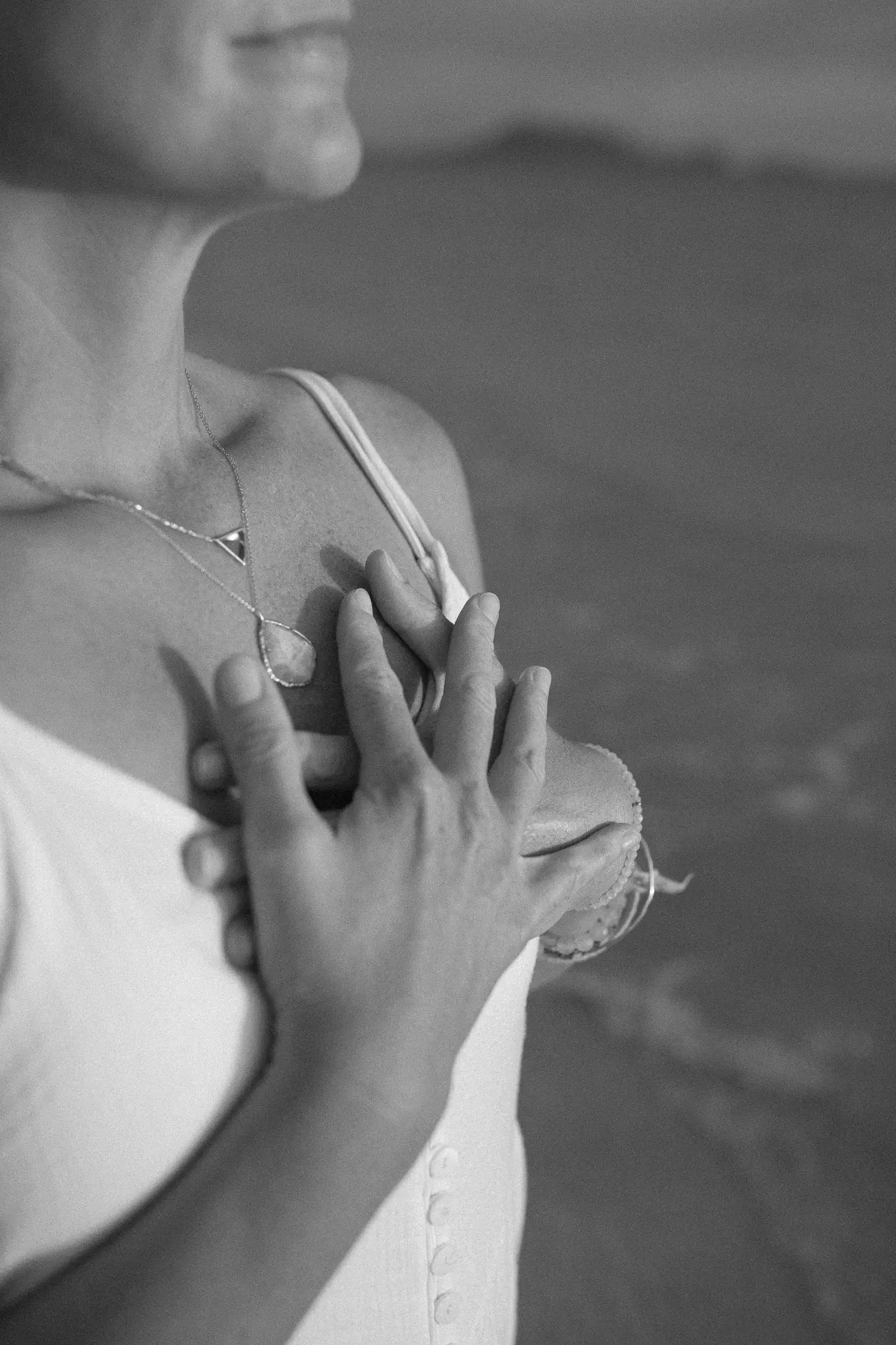 Black-and-white photo of a woman's hands resting gently over her heart