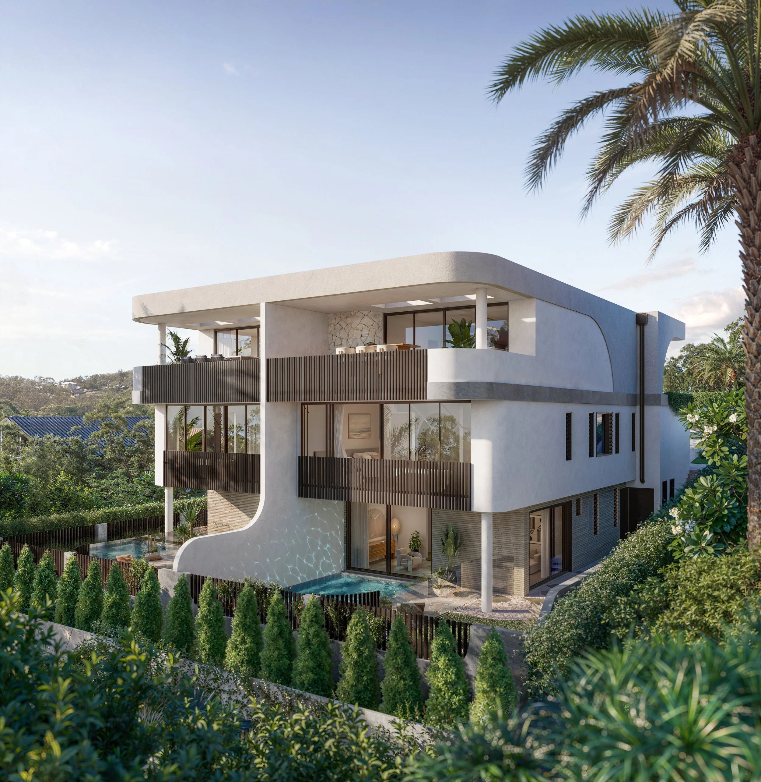 Modern white multi-story house with curved architectural design, large windows, and balconies surrounded by lush green trees and plants under a clear blue sky.