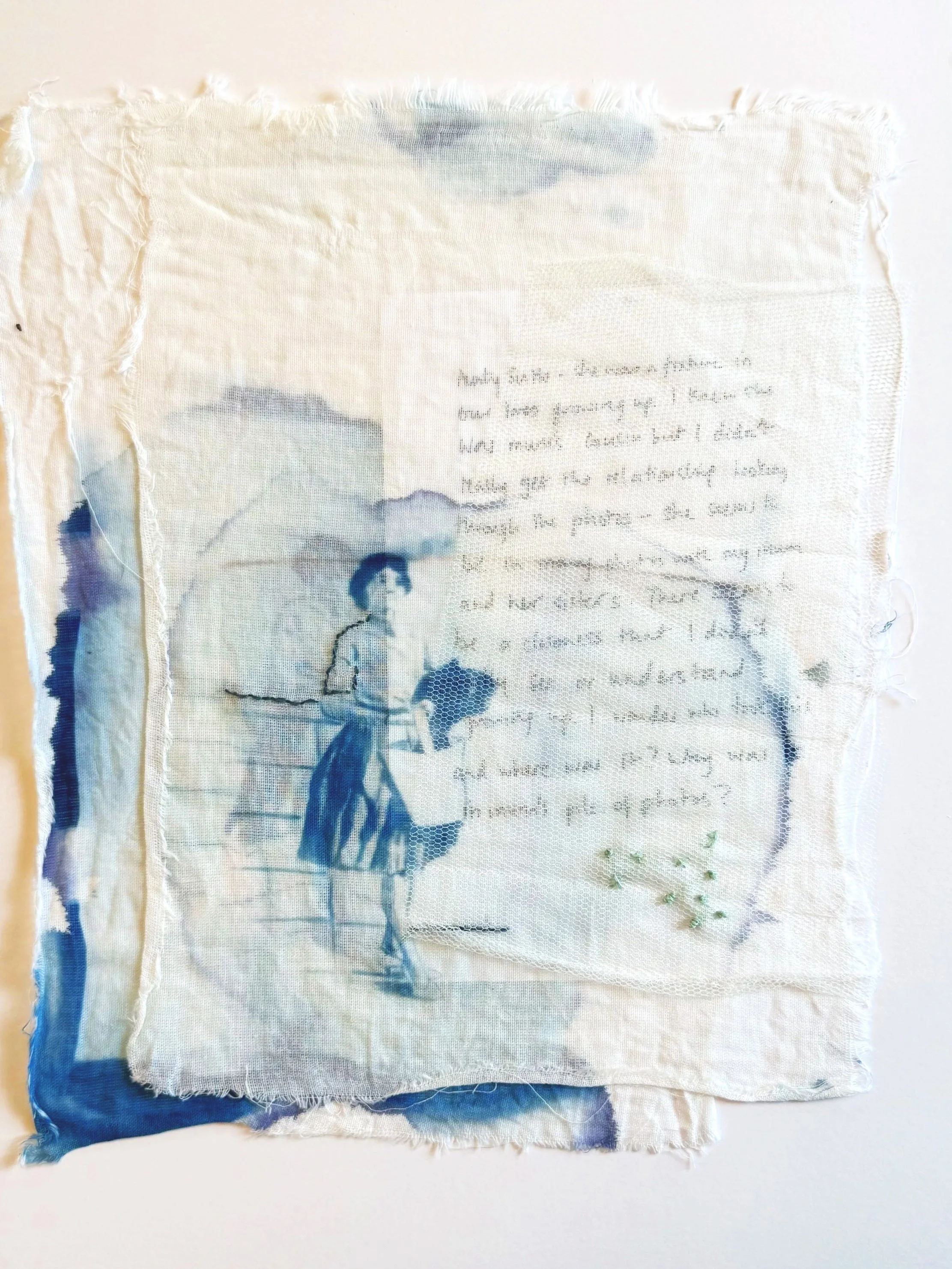 A piece of fabric with a cyanotype printed vintage photo of a woman standing on a street overlaying the handwritten text.