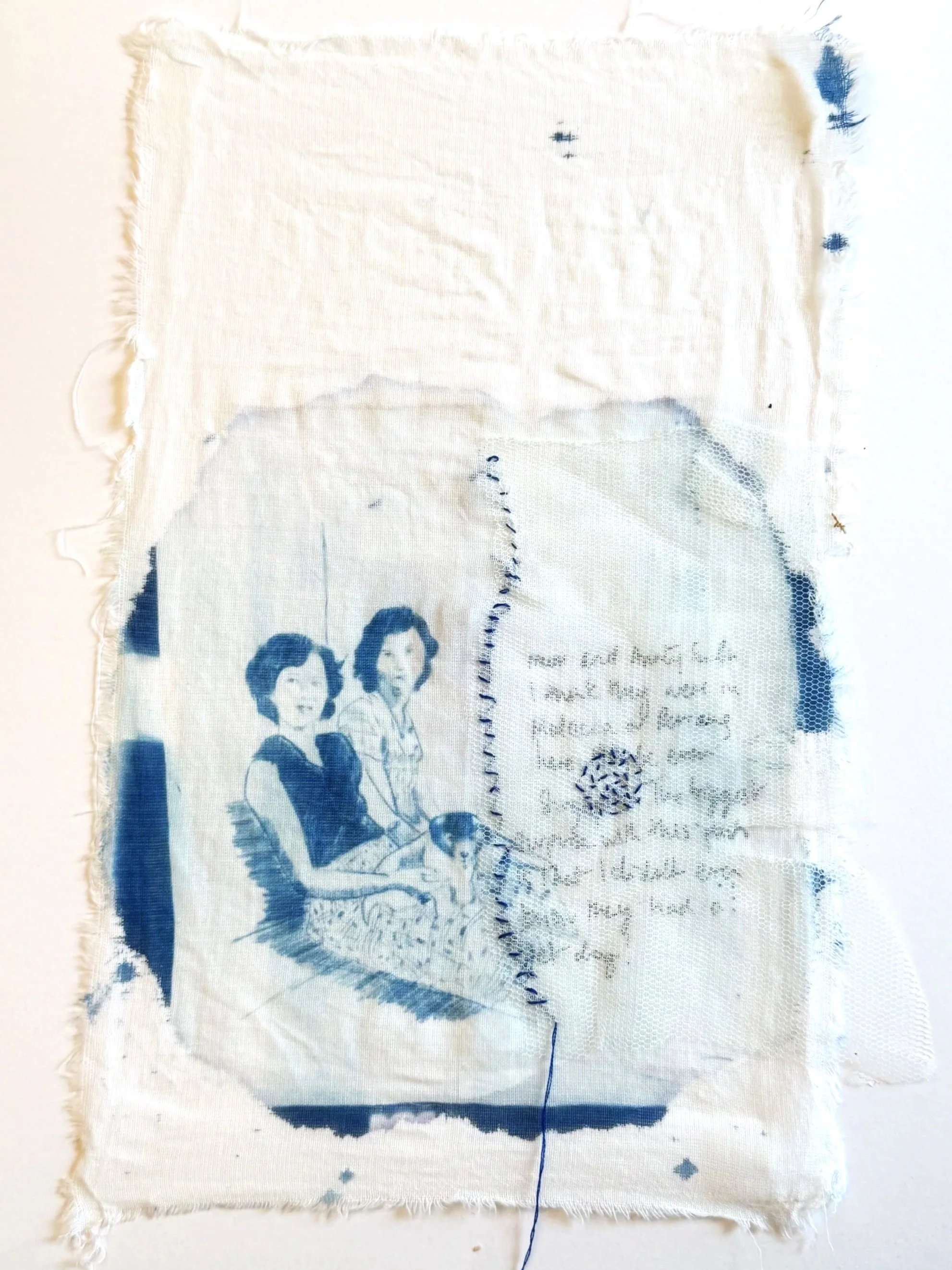 A piece of fabric with a printed photo of two women sitting together, one with short dark hair and the other with curly hair, both smiling. There is also some handwritten text and a decorative circular design on the fabric.