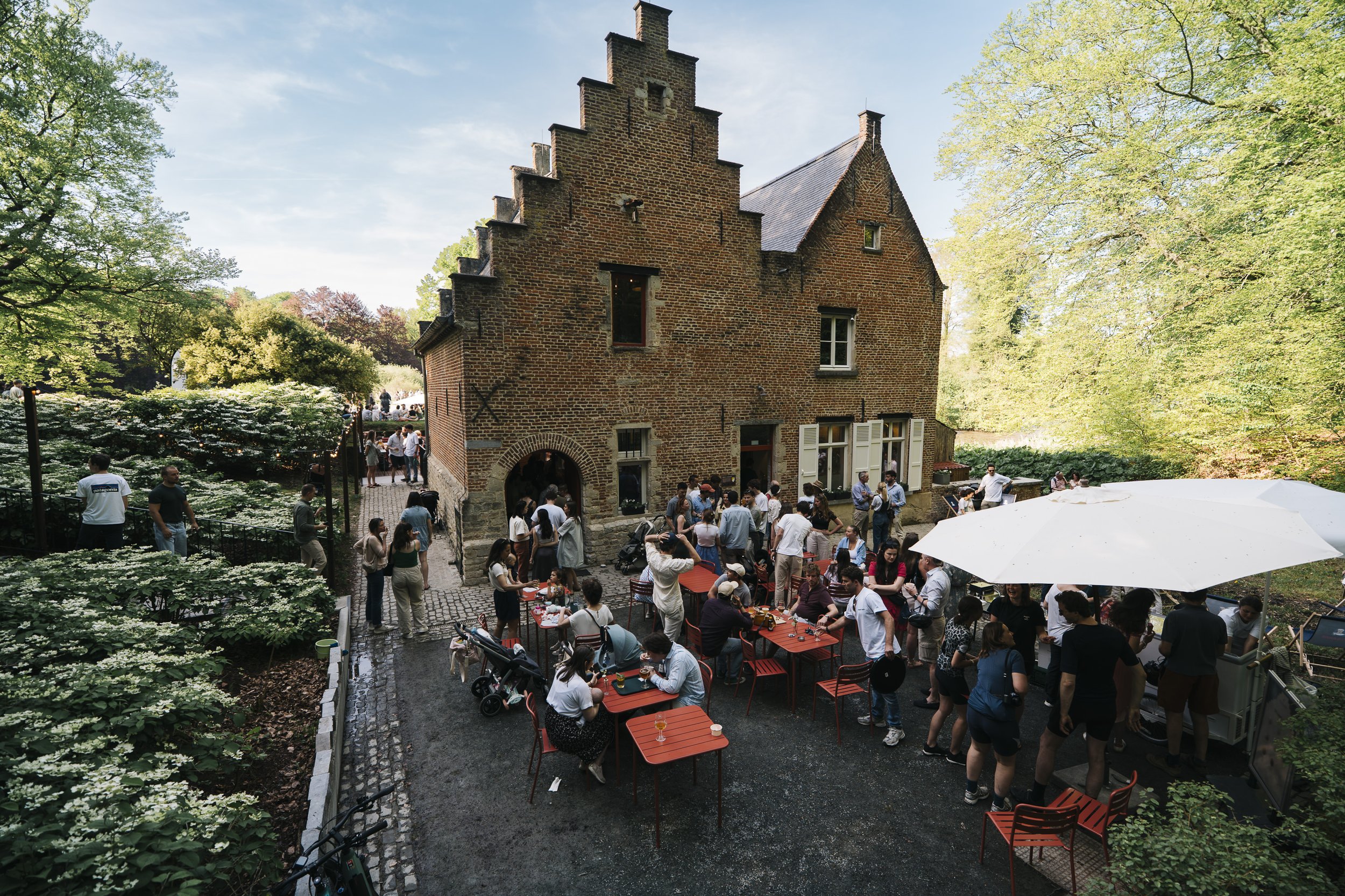 Photo of the Spaans Huis, with people around and a warm, welcoming atmosphere in the heart of Tervuren Park.
