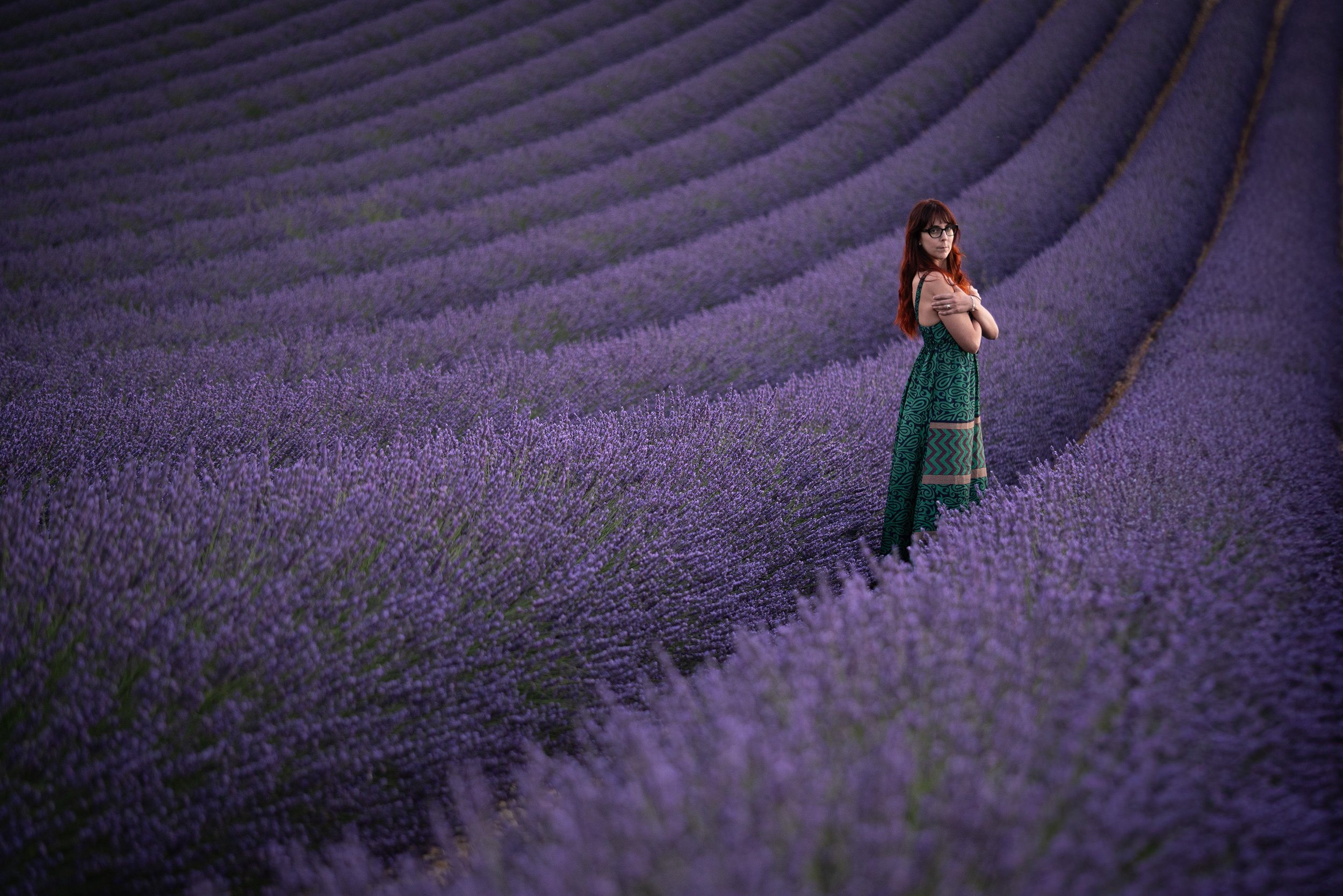 young woman with a green dress hug herself in a lavander field with purple flowers in valensole france