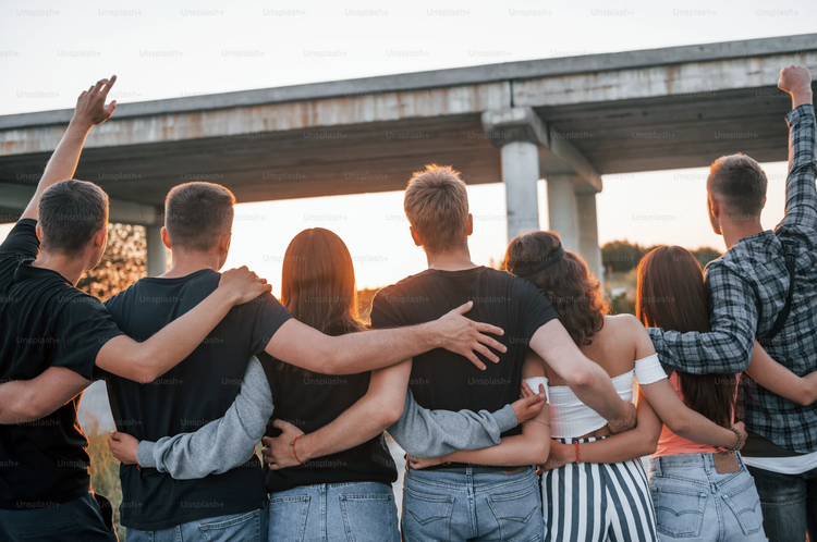 Junge Menschen stehen Arm in Arm und schauen in die Abendsonne