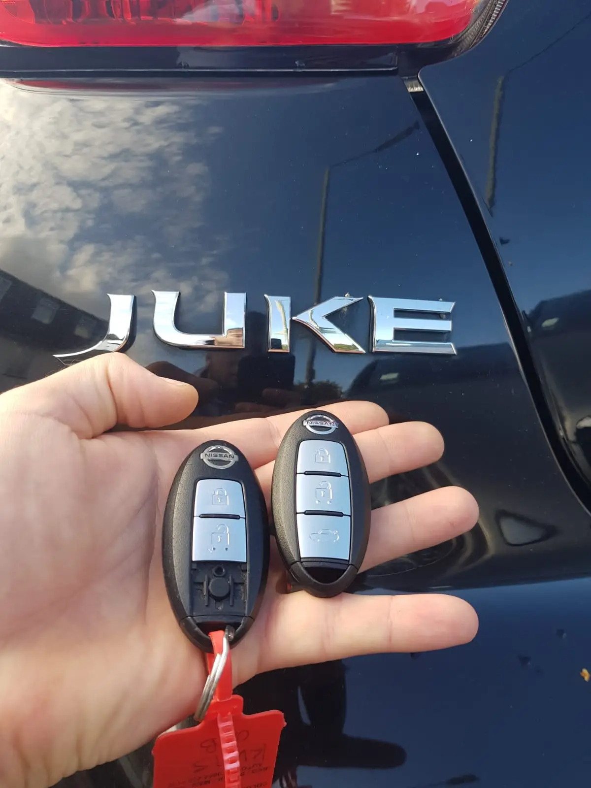To Nissan nøgler foran en sort bil med mærket 'Juke'.