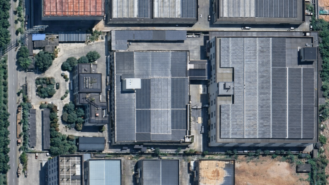 Aerial view of rooftops featuring solar panels in an urban area.