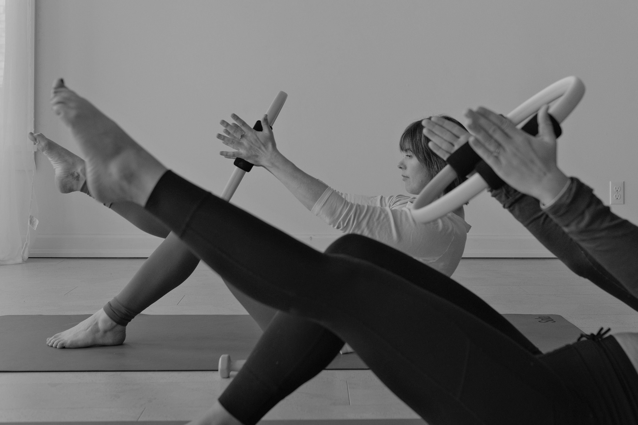 Two women doing Pilates exercise on mats with Pilates rings in a fitness room.
