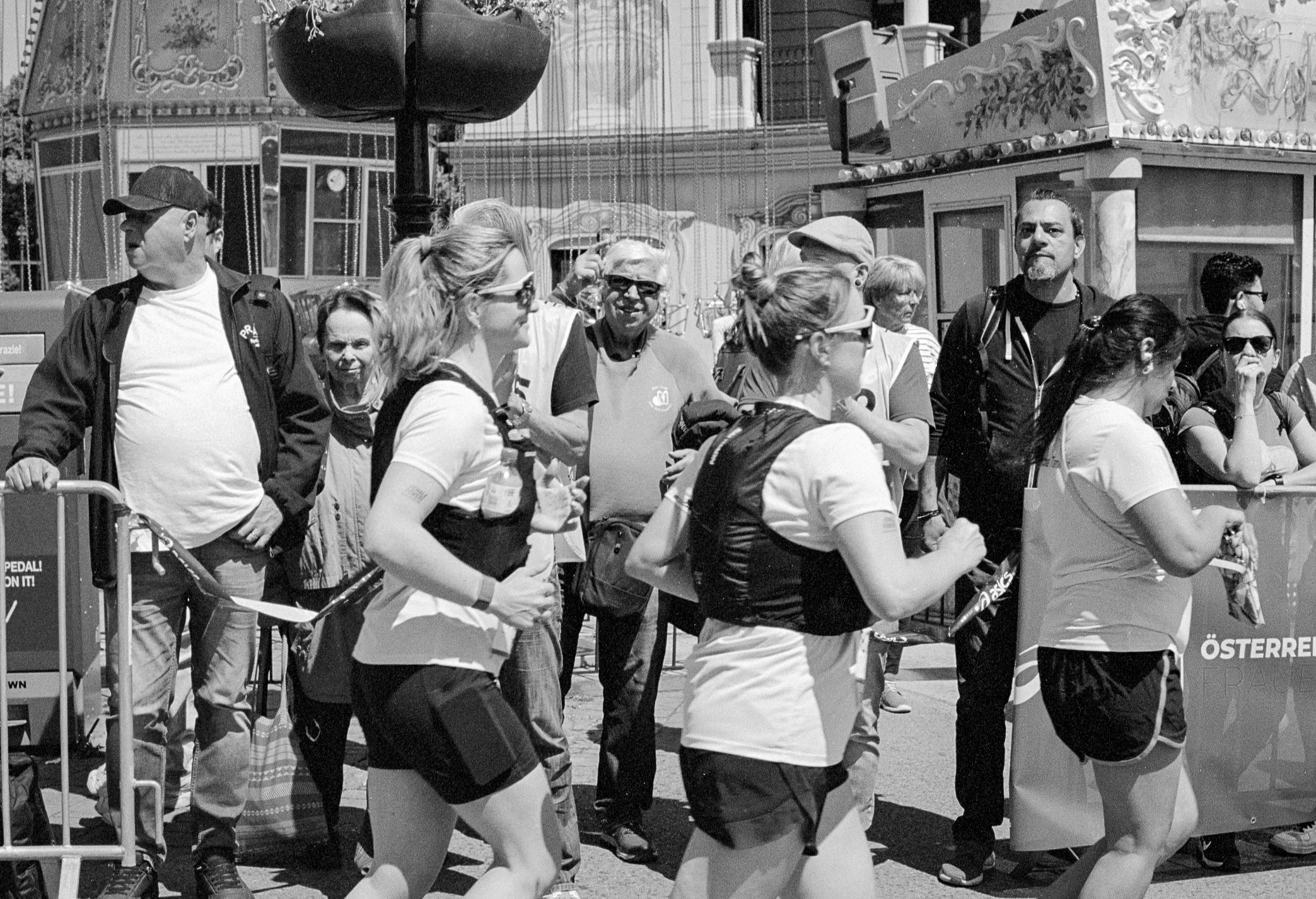People participating in a race or marathon, running outdoors in a city, with a diverse group of runners and spectators watching.