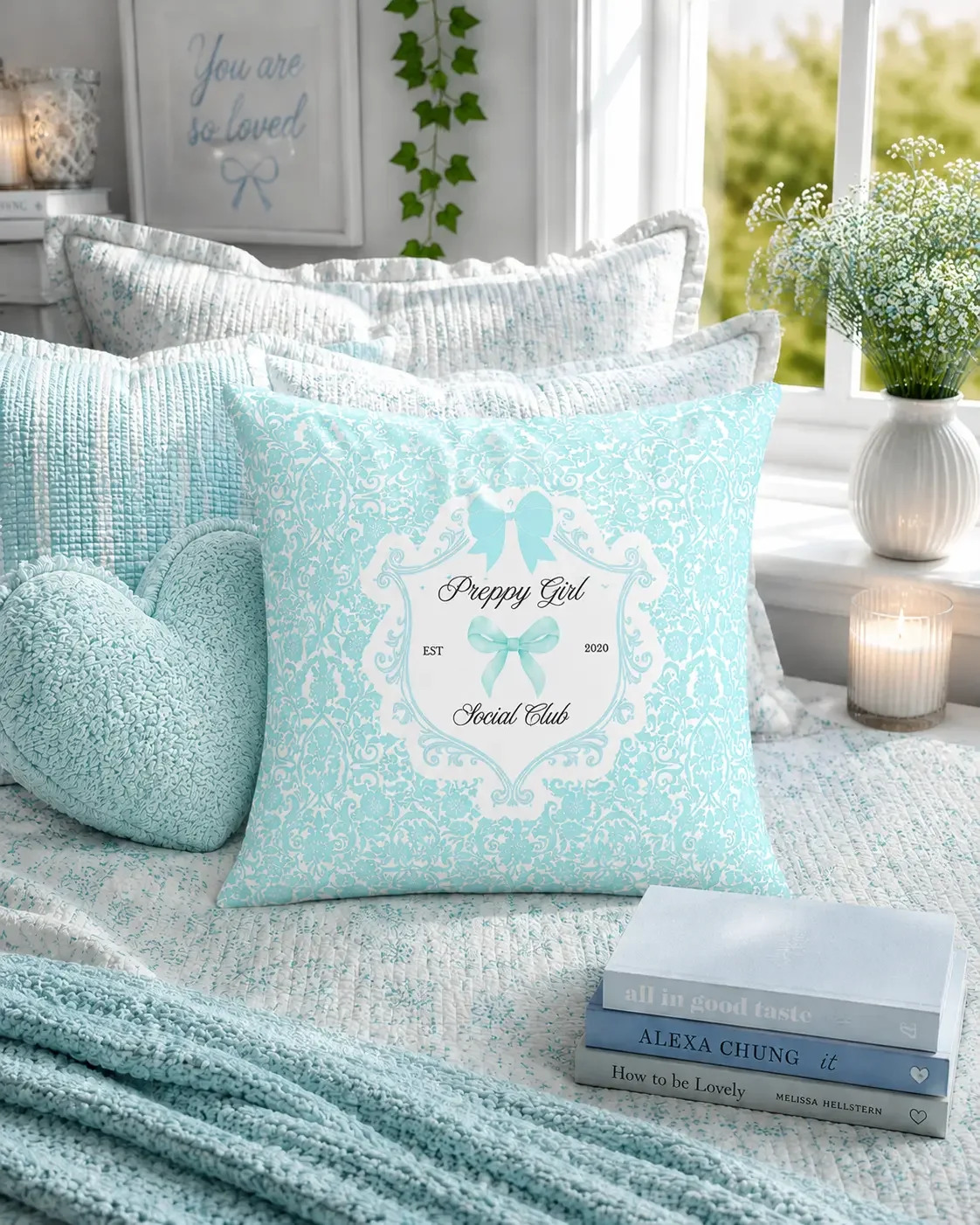 A square mint green damask throw pillow featuring a white decorative crest, light blue bows, and Preppy Girl Social Club text.