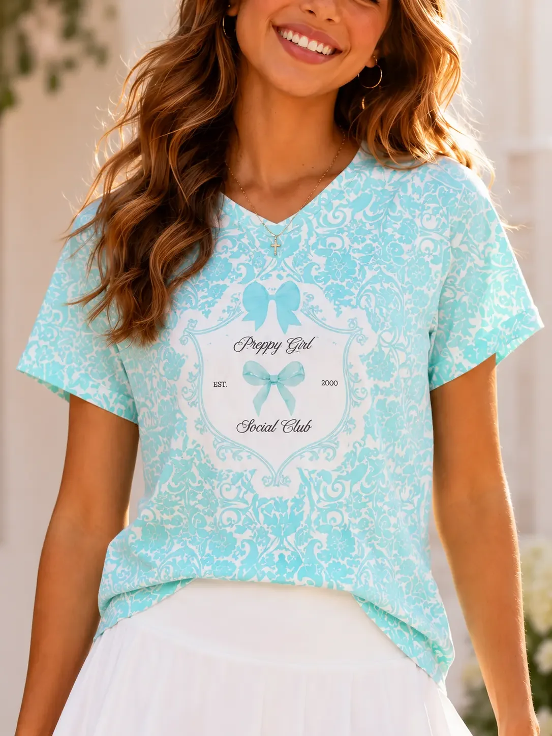 Close-up of a woman wearing a teal damask pattern "Preppy Girl Social Club" t-shirt with light blue coquette bows.