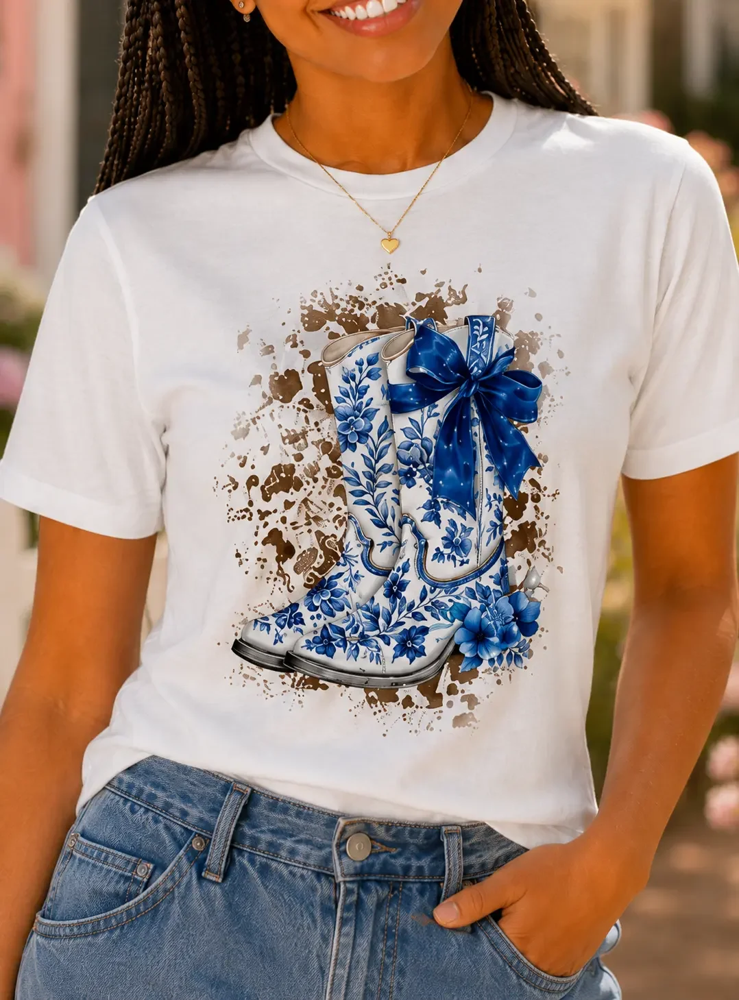 Close-up of a woman wearing a white t-shirt featuring a blue floral cowboy boots graphic with a large blue satin bow.