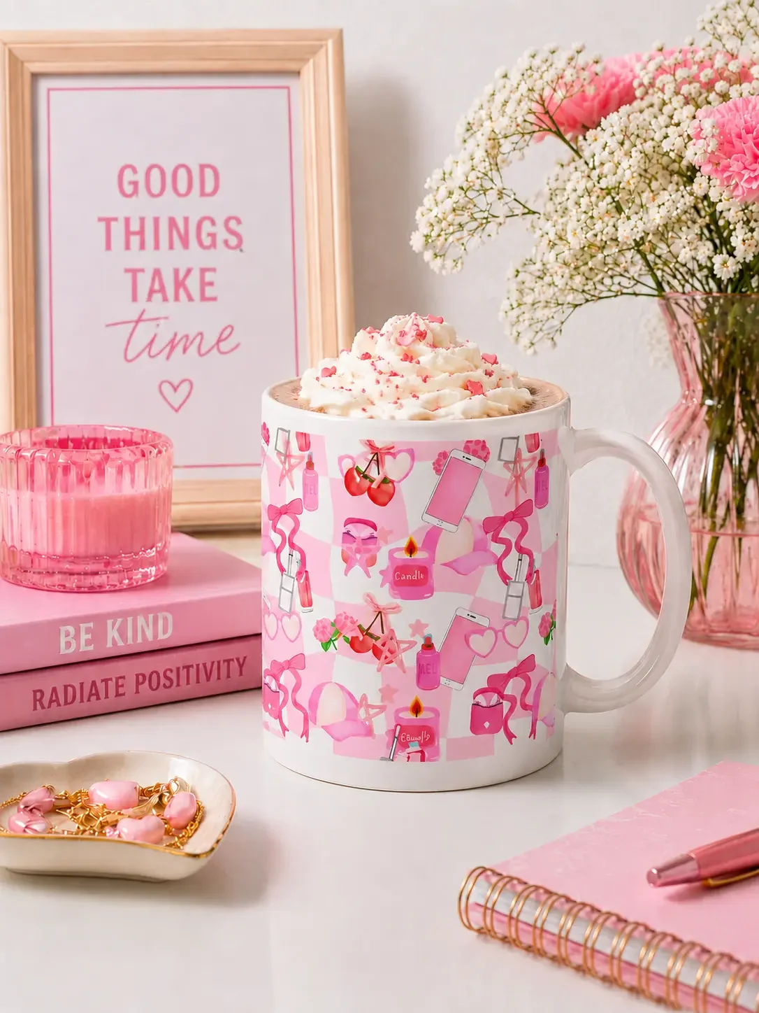 Pink coquette aesthetic mug filled with whipped cream and hot chocolate on a desk next to books and flowers.