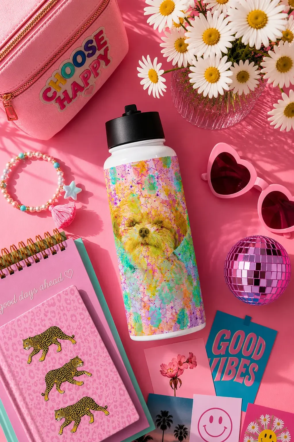 Top-down view of a colorful puppy water bottle with pink books, heart sunglasses, daisies, and a disco ball.
