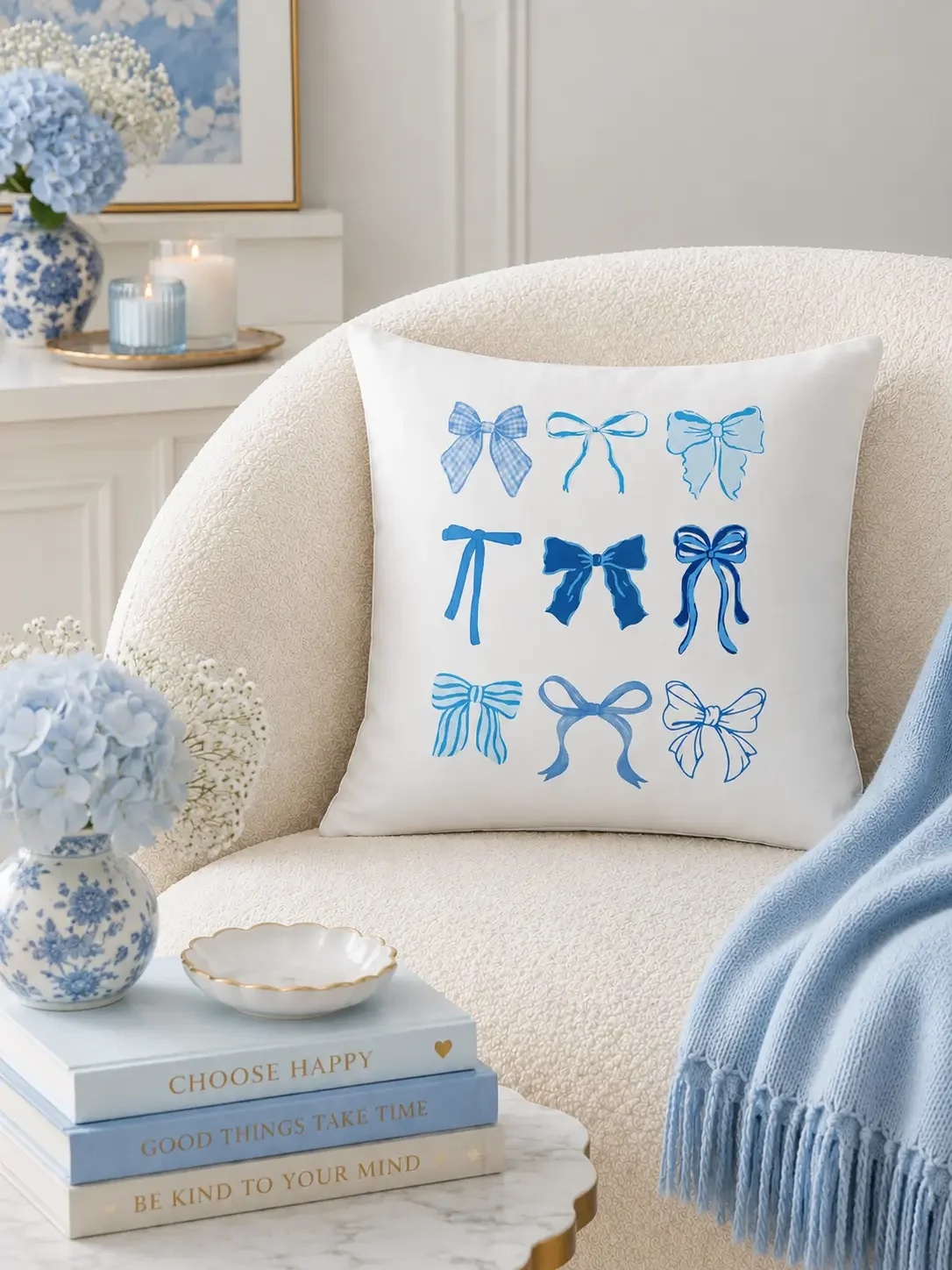 The Doodles and Saffron square white throw pillow featuring nine blue patterned coquette bows displayed on a white boucle accent chair.
