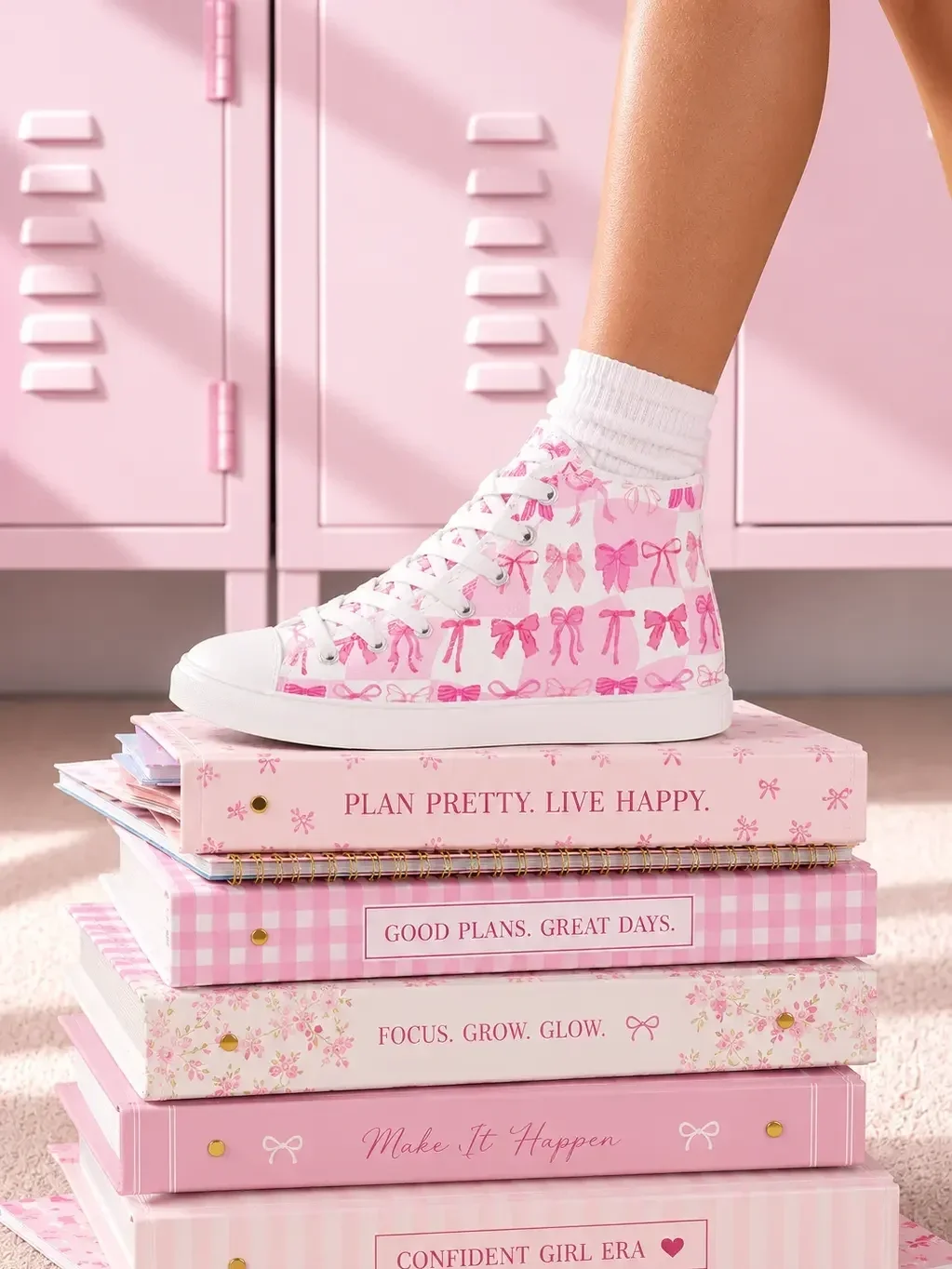 A person wearing pink checkered ribbon bow high-top sneakers standing on a stack of pink inspirational school journals.